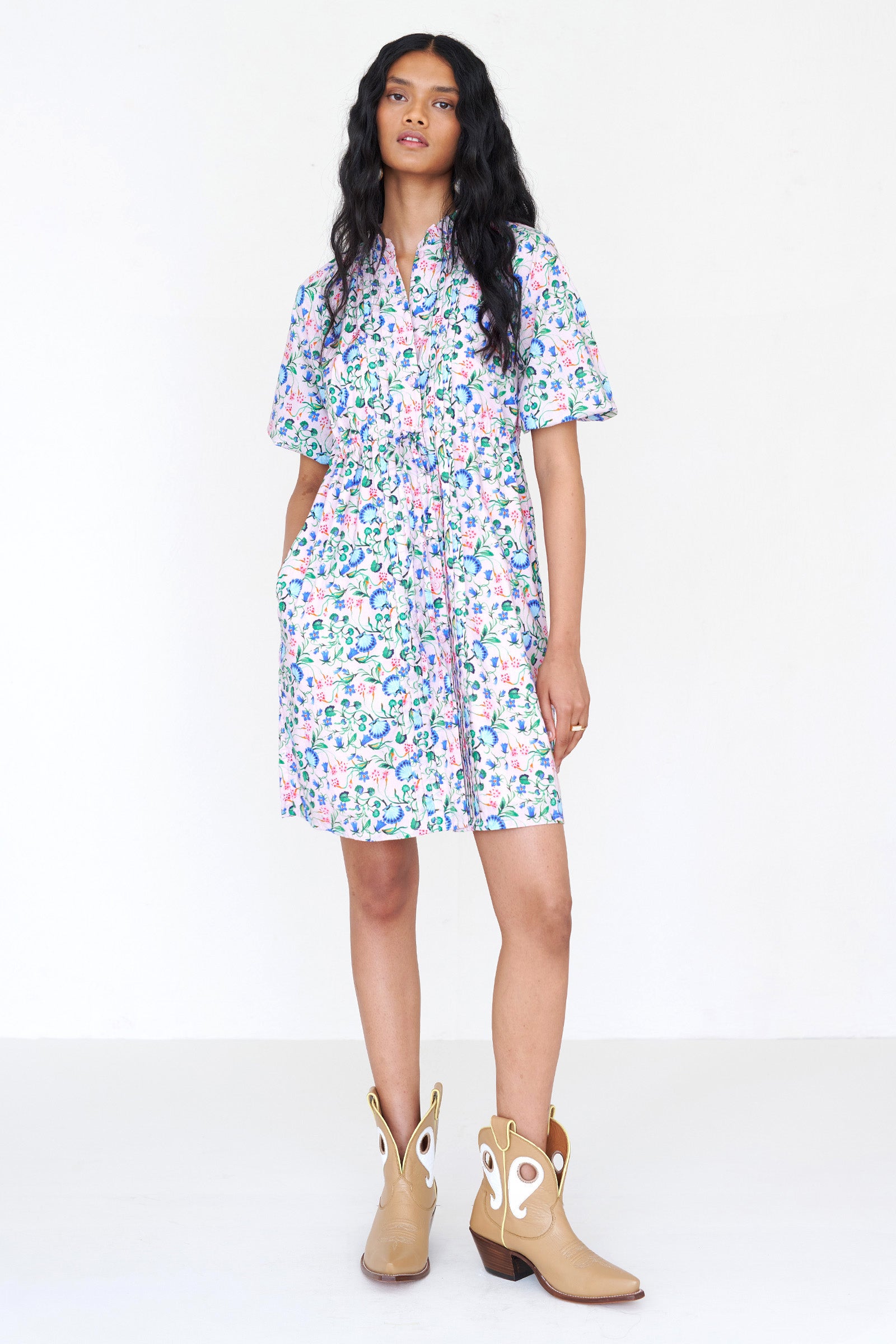 Front view of a woman standing. She is wearing the Benita shirtdress in Clam Garland print, featuring a buttoned front placket, drawstring waist, contrast-print trim and side-seam pockets.