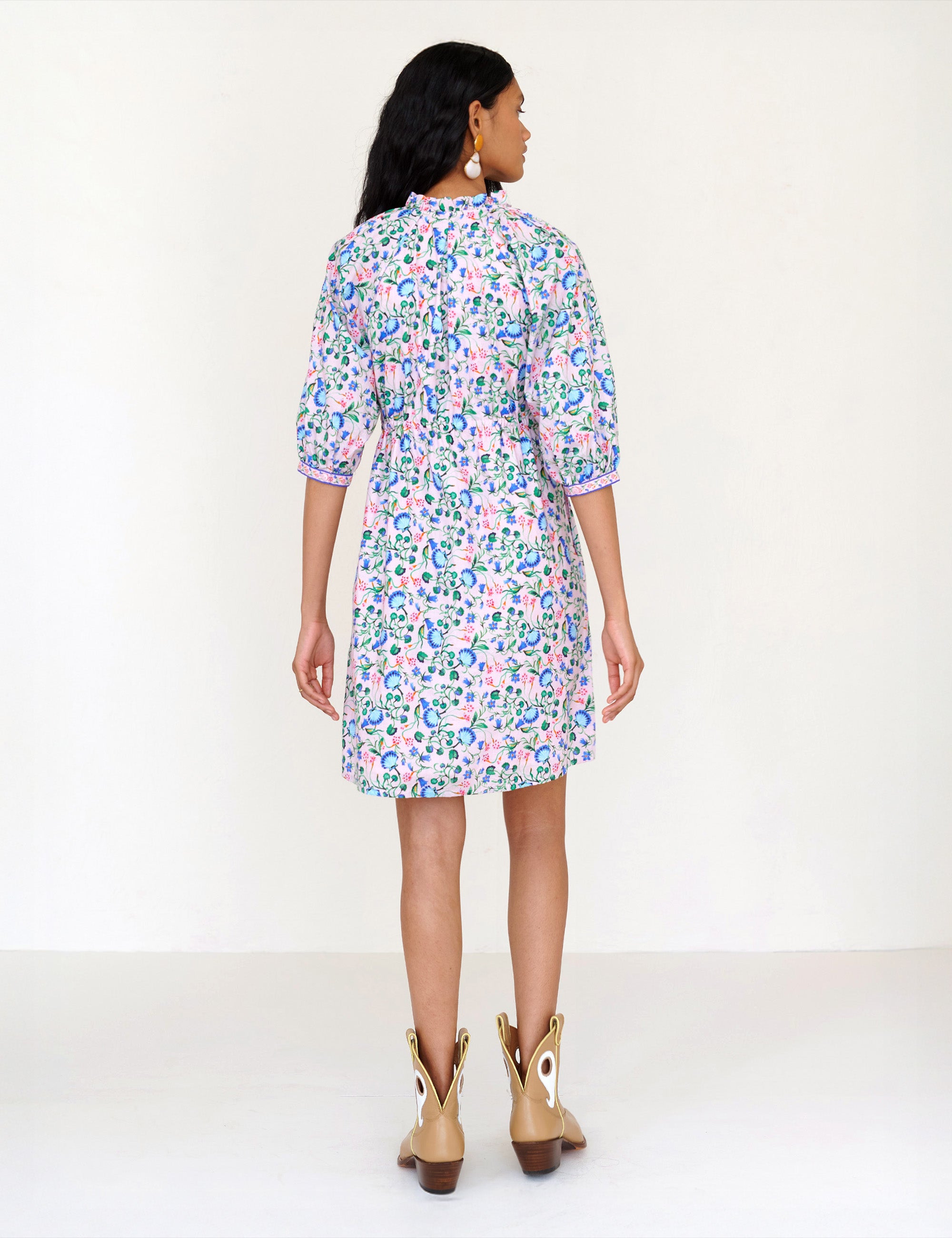 Back view of a woman standing. She is wearing the Benita shirtdress in Clam Garland print. It features a button-front placket, contrast-print trim, drawstring waist, and side-seam pockets.