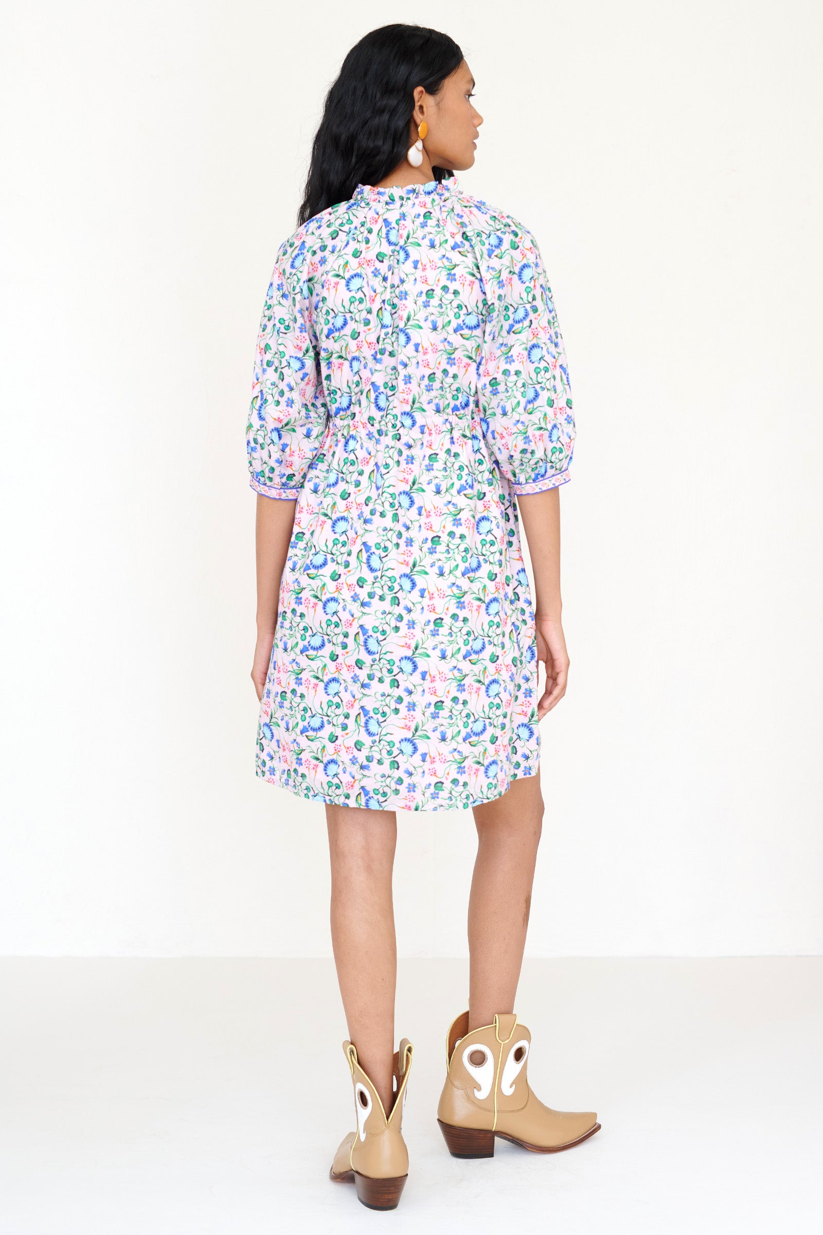 Back view of a woman standing. She is wearing the Benita shirtdress in Clam Garland print, featuring a buttoned front placket, drawstring waist, contrast-print trim and side-seam pockets.