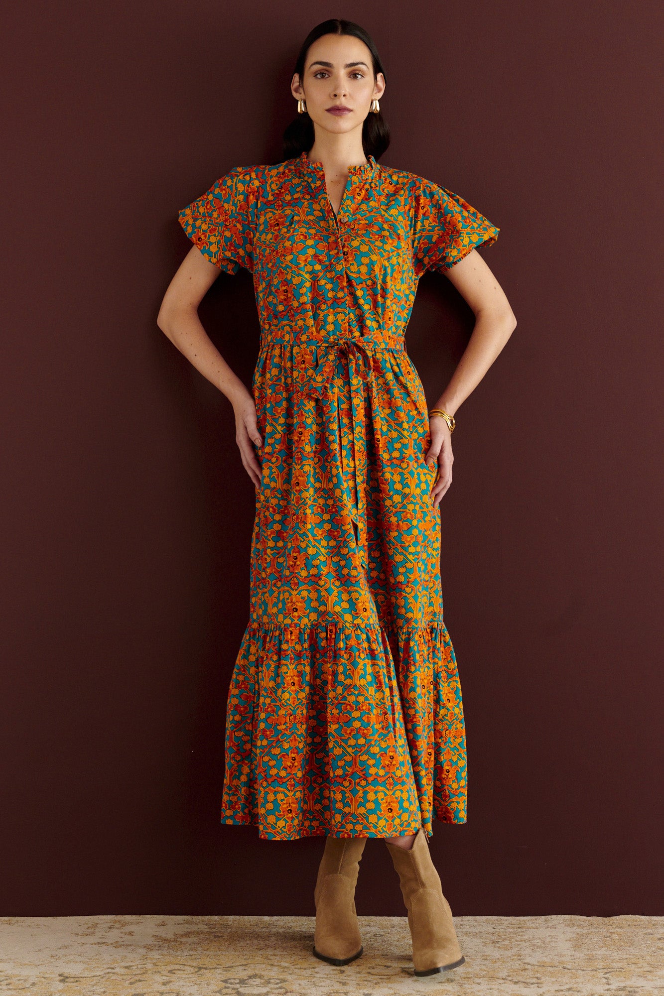 Front view of woman standing. She is wearing the Betty dress in Ottoman print. It has nipped waist, full gathered skirt, tucked raglan sleeves, cotton voile fabric, fabric tie belt, fully lined construction, and side-seam pockets.