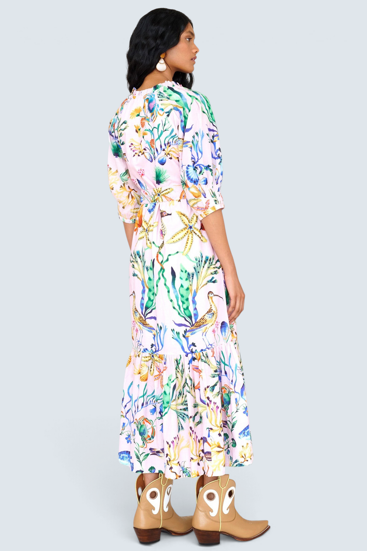 Back view of a woman standing. She is wearing the Betty dress in Tidepool print. It features a nipped waist, voluminous gathered skirt, tucked raglan sleeves, fabric tie belt & pockets.
