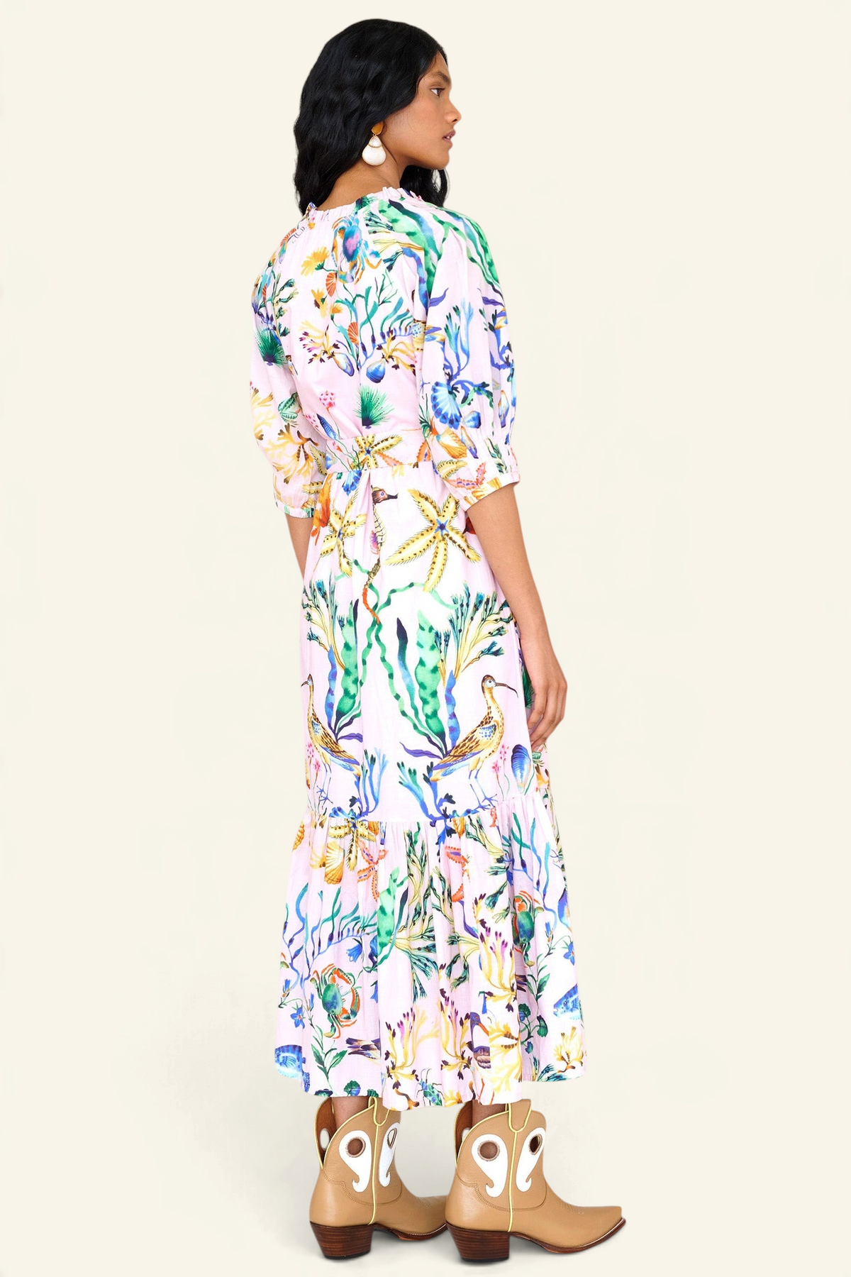 Back view of a woman standing. She is wearing the Betty dress in Tidepool print. It features a nipped waist, voluminous gathered skirt, tucked raglan sleeves, fabric tie belt & pockets.