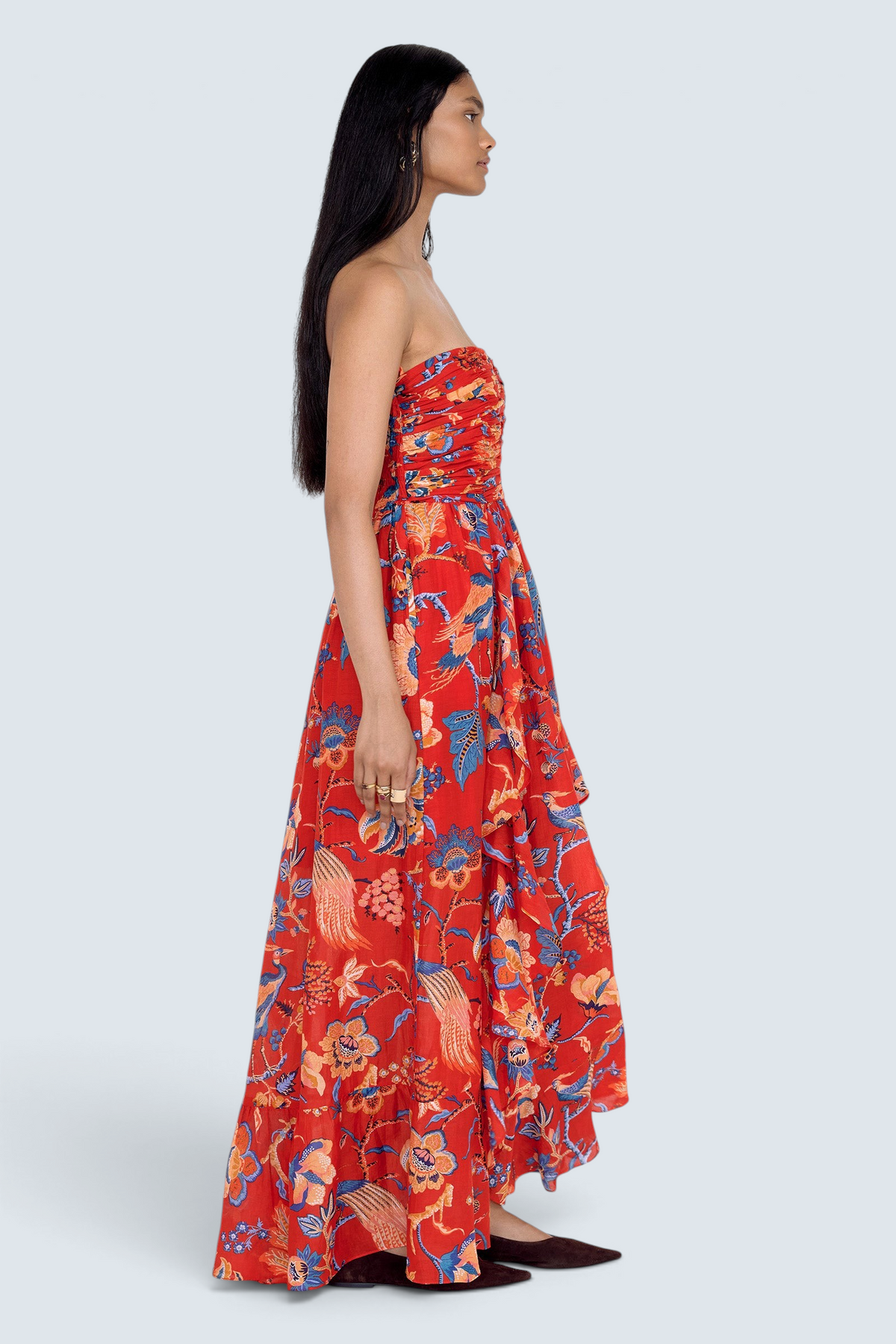 Side view of model standing. She is wearing the Bella dress in Chintz print. It features a full-length cascading skirt, subtle frill detail, ruched bodice, and smocked back.