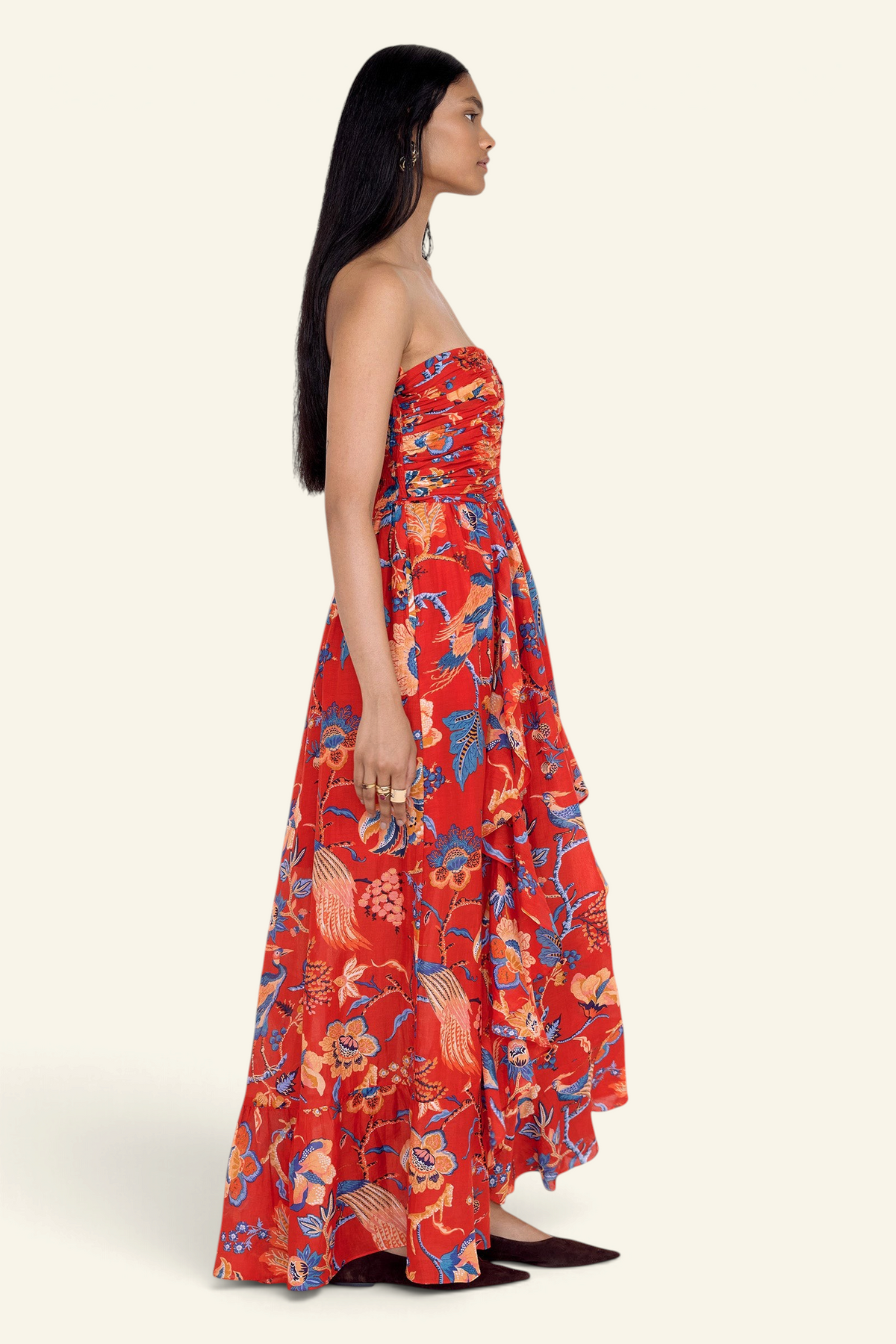 Side view of model standing. She is wearing the Bella dress in Chintz print. It features a full-length cascading skirt, subtle frill detail, ruched bodice, and smocked back.