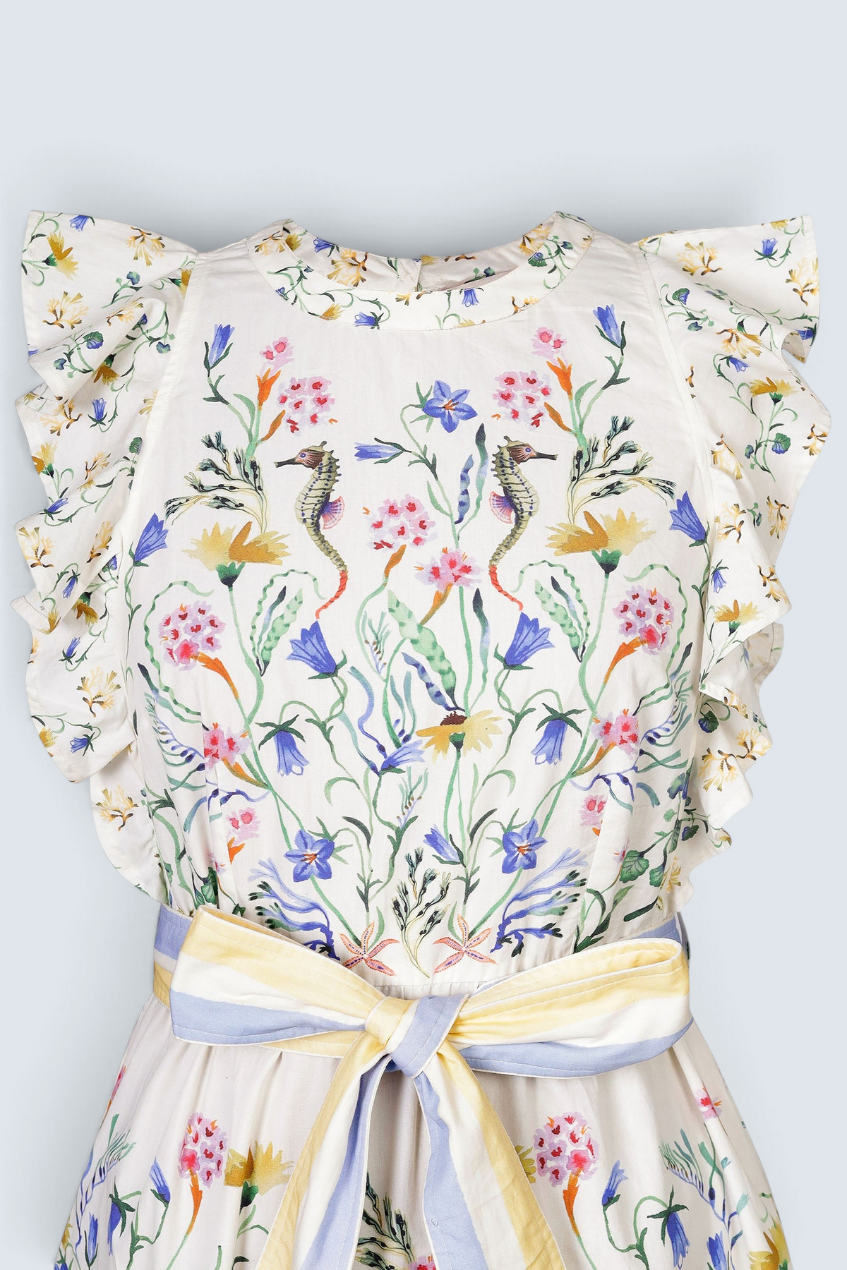 Banjanan Bulbul dress in Tidepool Grotto print with ruffled shoulders, seahorse floral pattern, and striped belt.