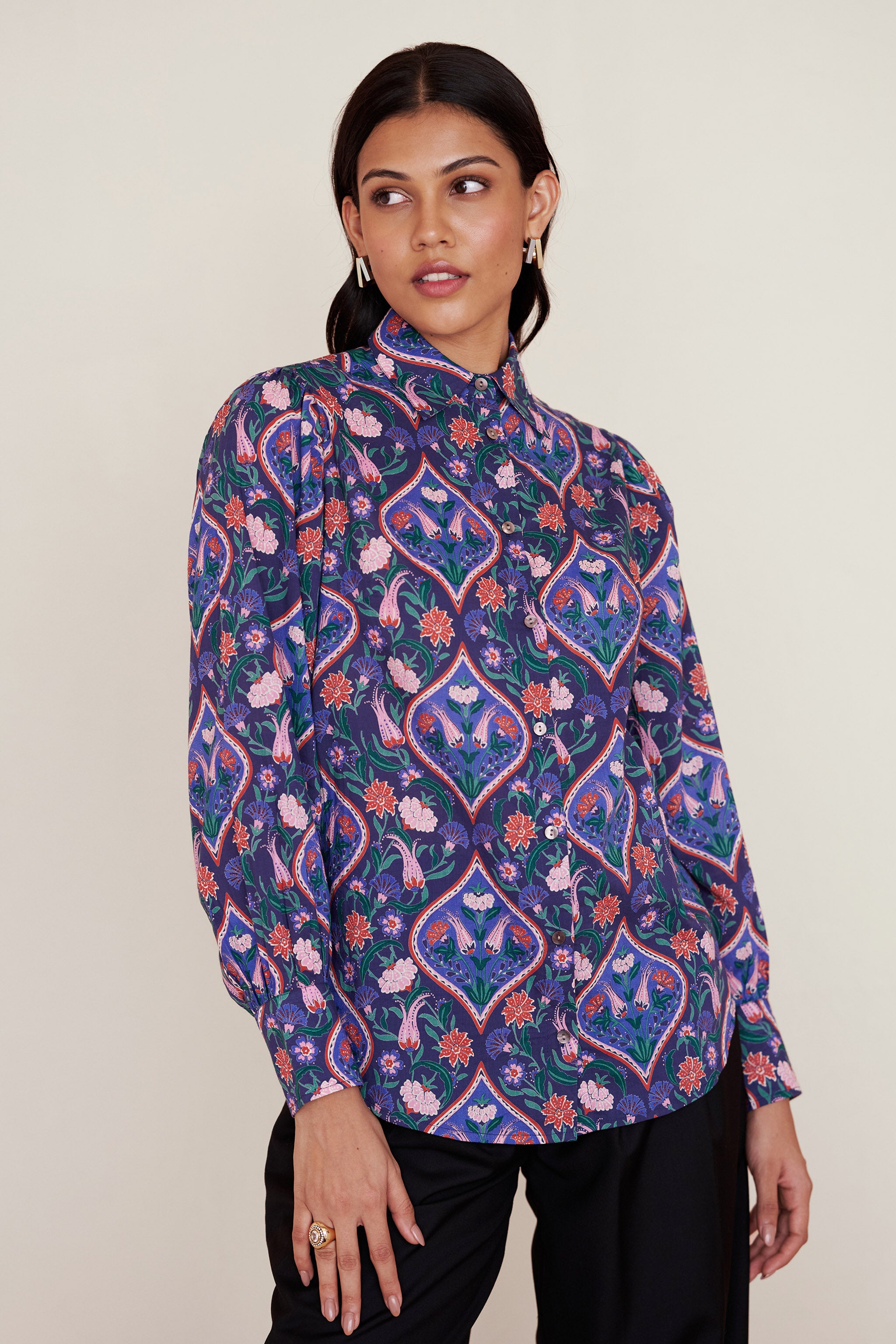 Front view of woman wearing a Cora Shirt in Persian Tile Lapis print. It is a relaxed-fit button-down shirt with floral tile print, straight collar, and full sleeves with buttoned cuffs.