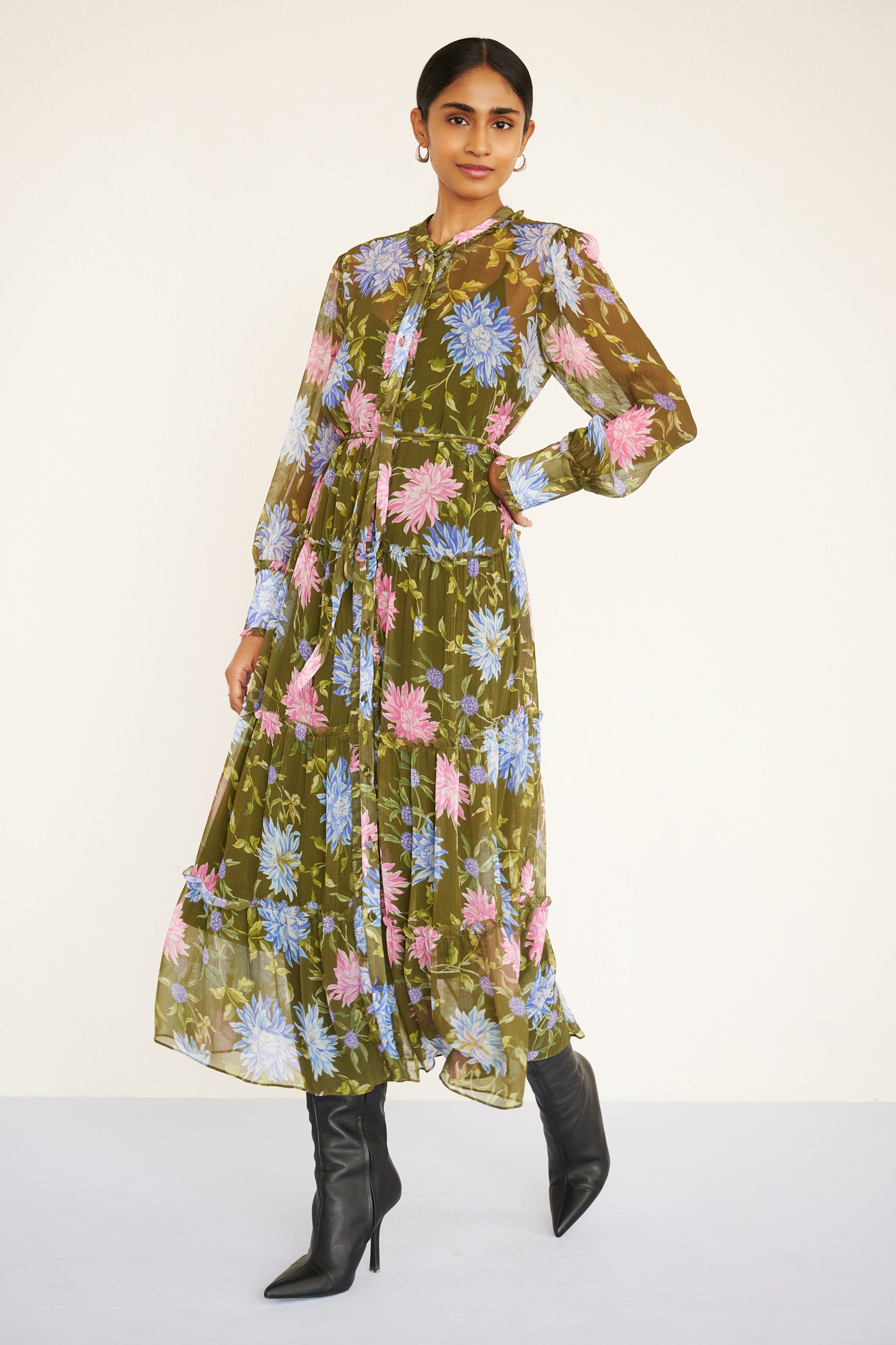 Side view of woman wearing a long-sleeve chiffon midi dress with sheer sleeves, ruffle details, fabric buttons, and a painterly floral print, styled with a detachable belt.