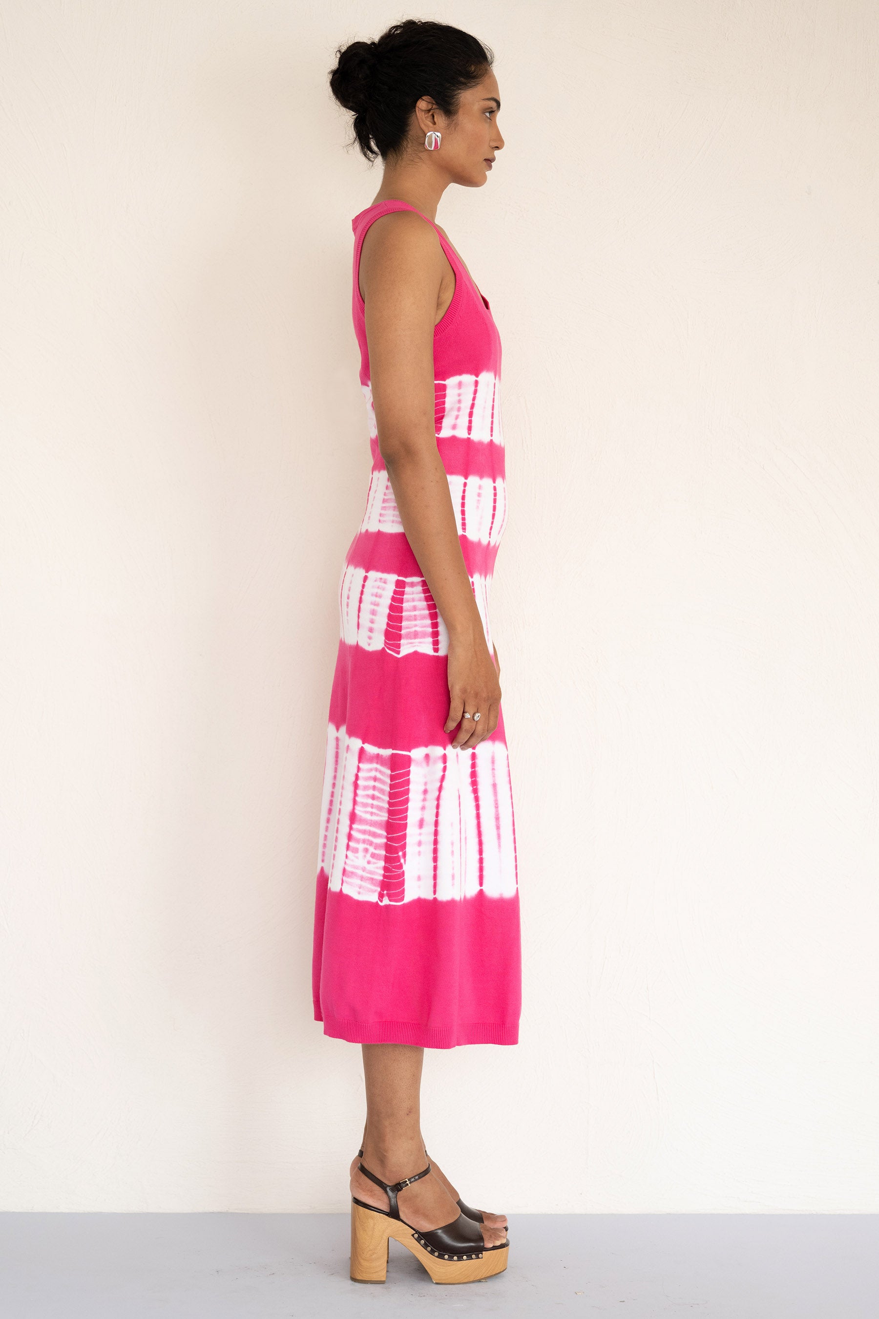 Side view of model wearing a sleeveless and calf length Genoa tie dyed dress. Side view of model wearing a sleeveless and calf length Genoa tie dyed dress.