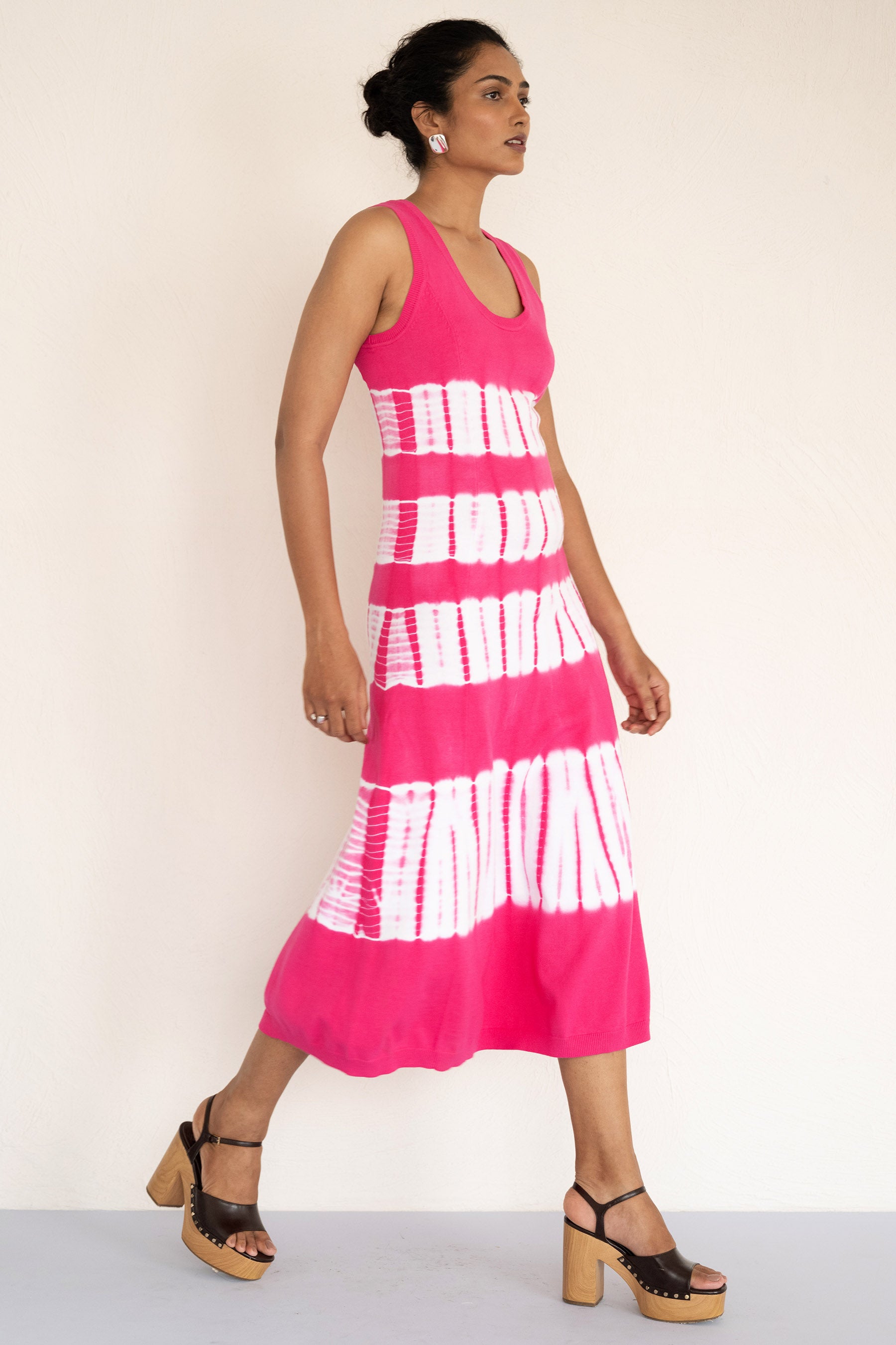 Model posing sideways wearing a sleeveless and calf length Genoa tie dyed dress. Model posing sideways wearing a sleeveless and calf length Genoa tie dyed dress.