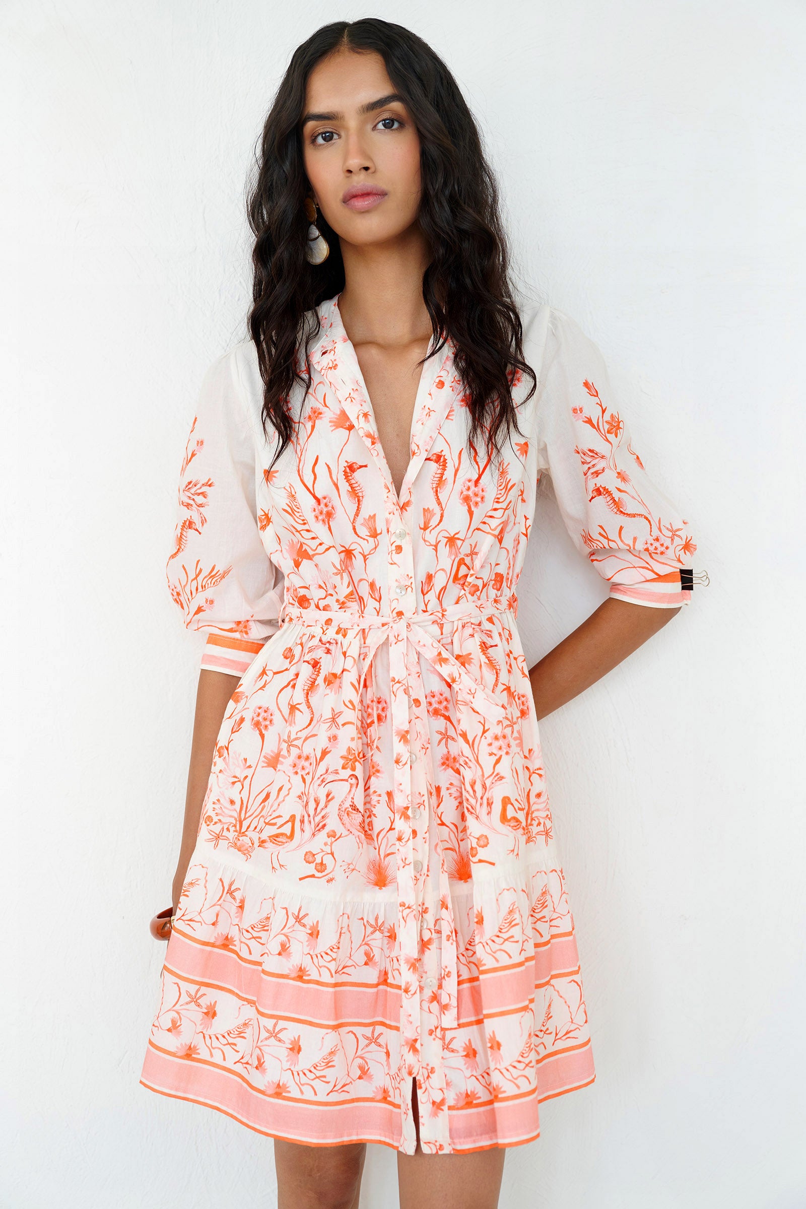Front side view of a woman standing wearing the Gizela shirtdress in Tidepool print, featuring a round neckline, buttoned cuffs & self-tie waist belt.