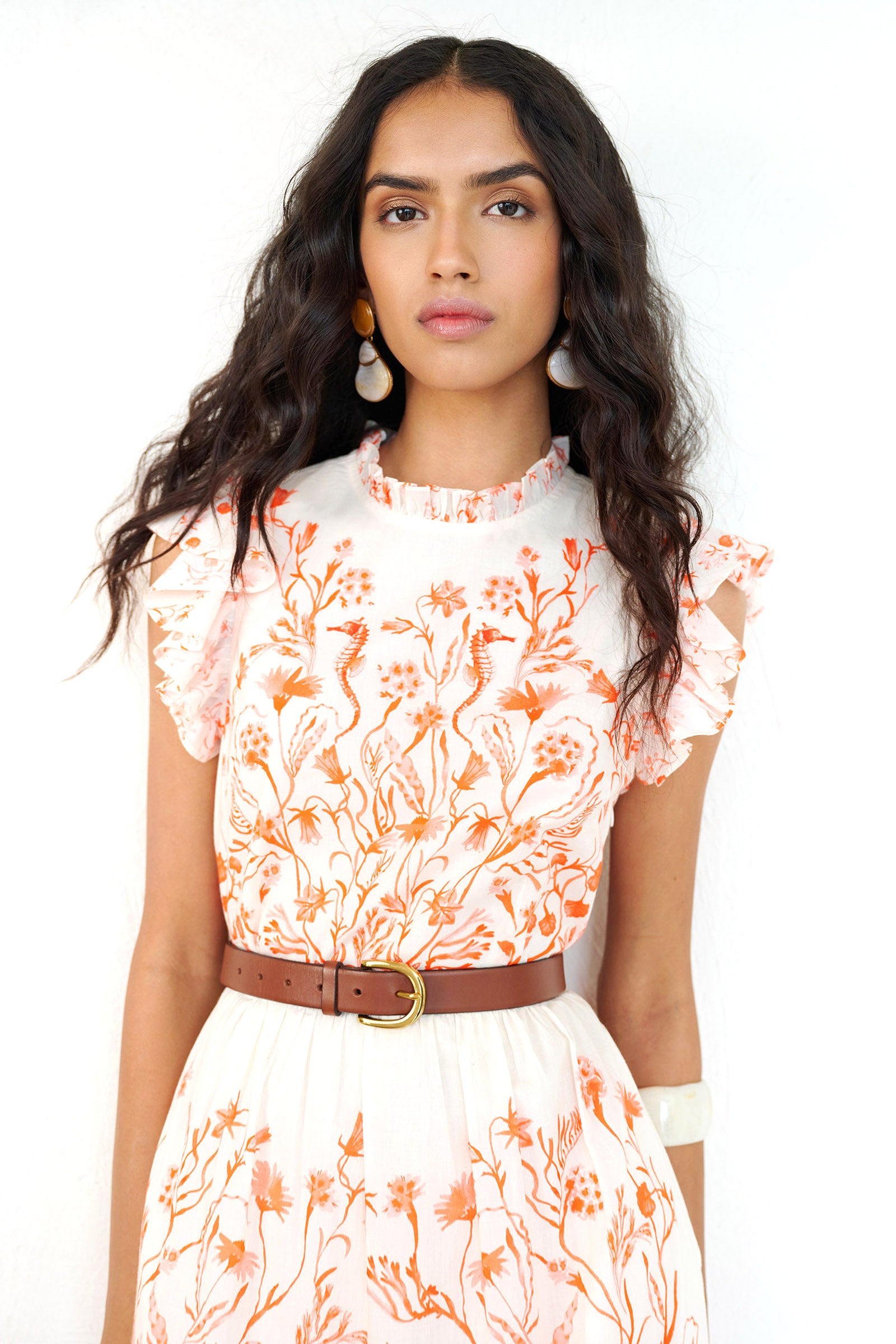 Front view close up of a woman standing wearing the Hannah dress in Tidepool print. It features ruffled neckline, tiered skirt, back keyhole with button closure & side-seam pockets.