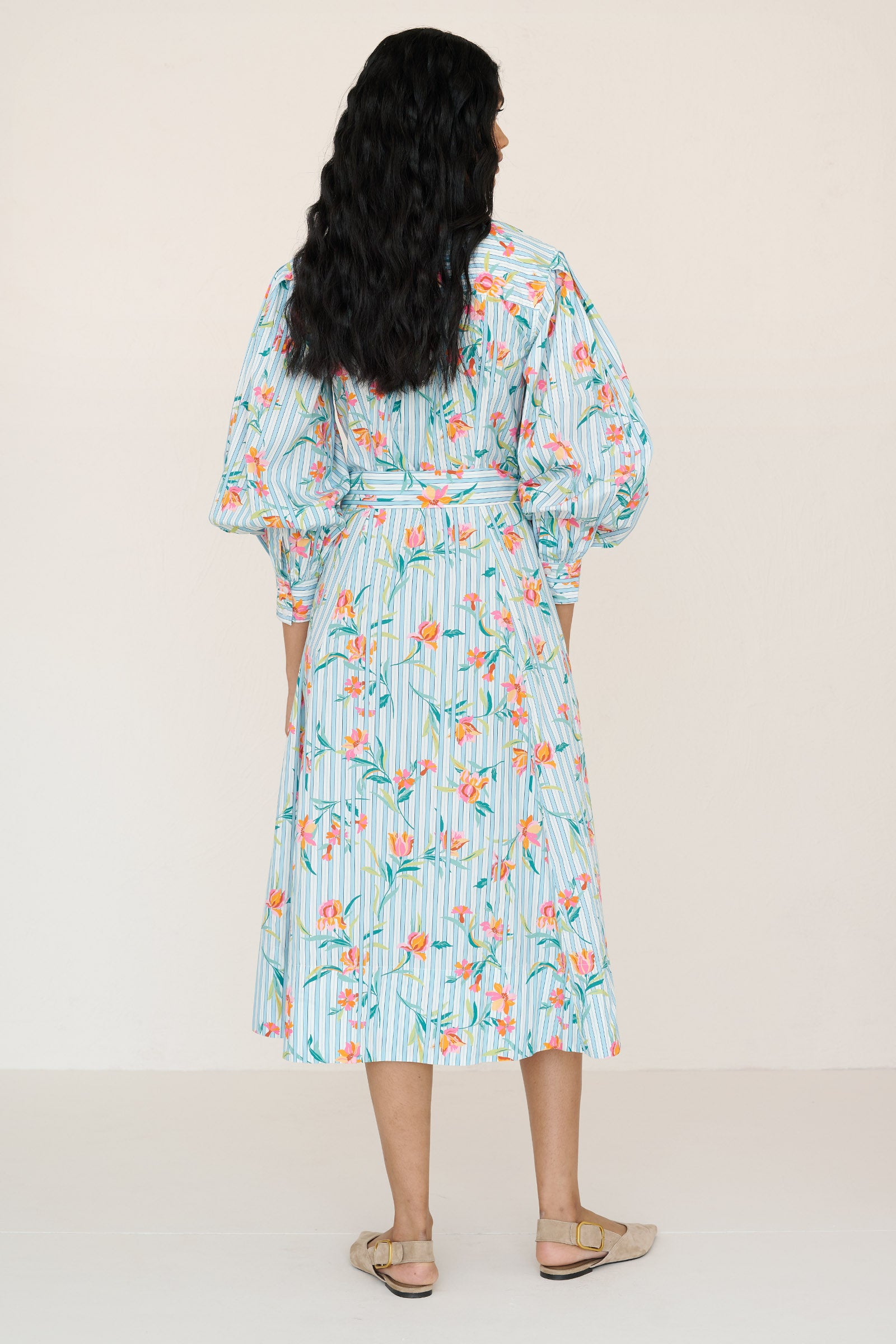 Back view of a woman standing wearing the Harris shirtdress in orchid stripe print, featuring a fitted bodice with princess seams, fabric tie belt, flared skirt with godets, and a classic button-front silhouette.