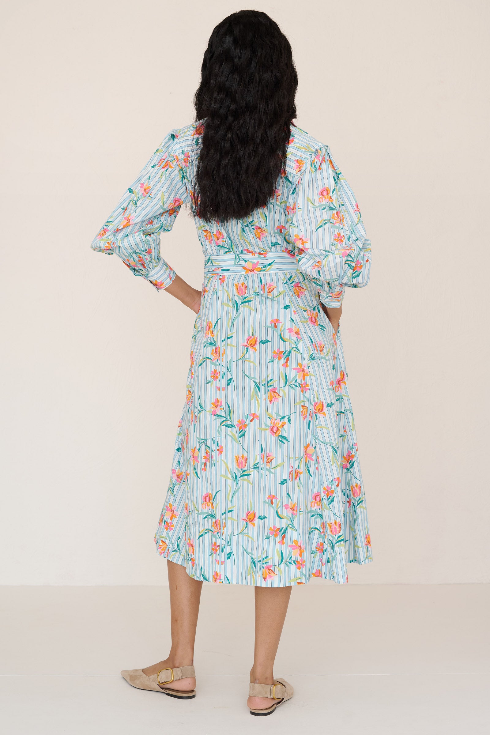 Back view of a woman standing wearing the Harris shirtdress in orchid stripe print, featuring a fitted bodice with princess seams, fabric tie belt, flared skirt with godets, and a classic button-front silhouette.