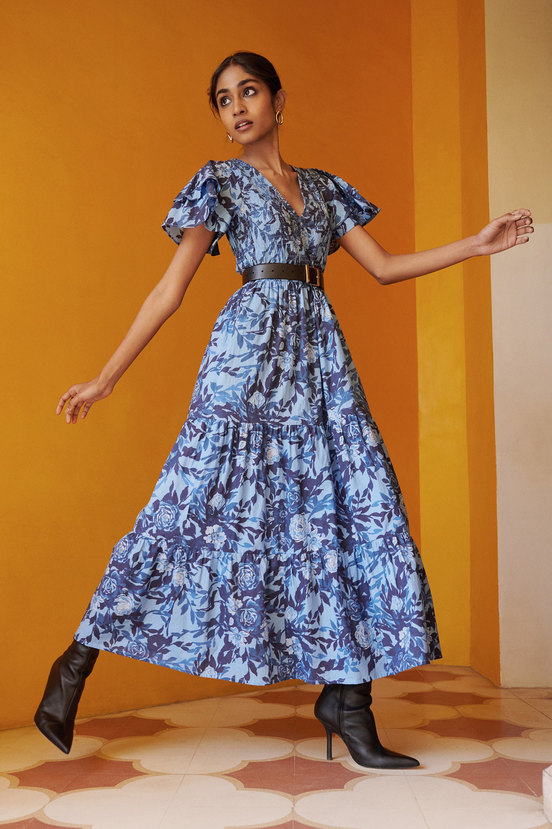 Woman posing wearing Ira Dress in Bibi Rose Clematis print. The dress is styled with black boots and a black belt.