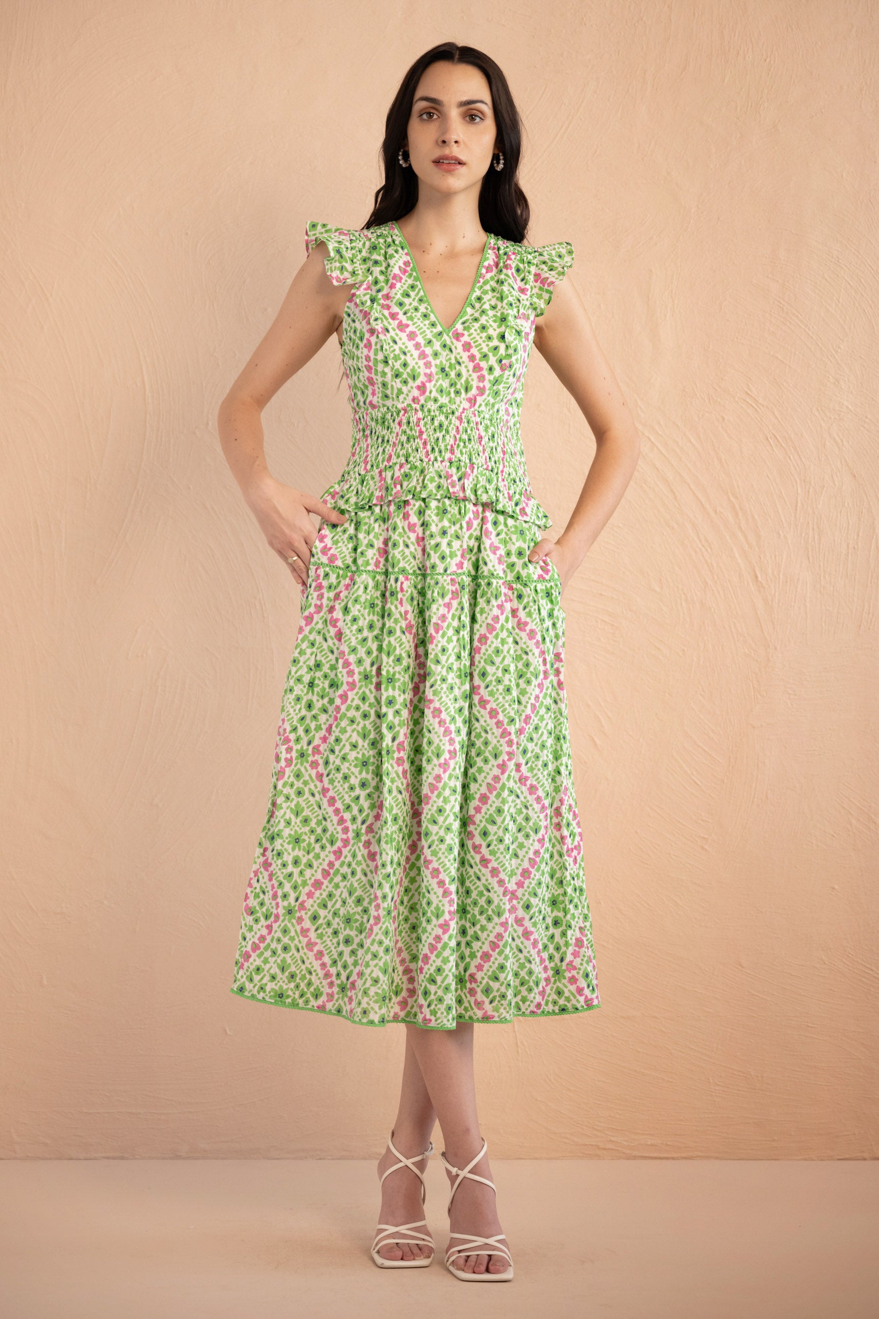 Front view of the Keira dress in a fresh green and pink Athena Heart print with floral and heart motifs. The dress features lace trim along the neckline and sleeves, a smocked waist for a flattering fit, and soft frill accents. The A-line skirt falls to the shin, and the dress includes discreet side pockets.