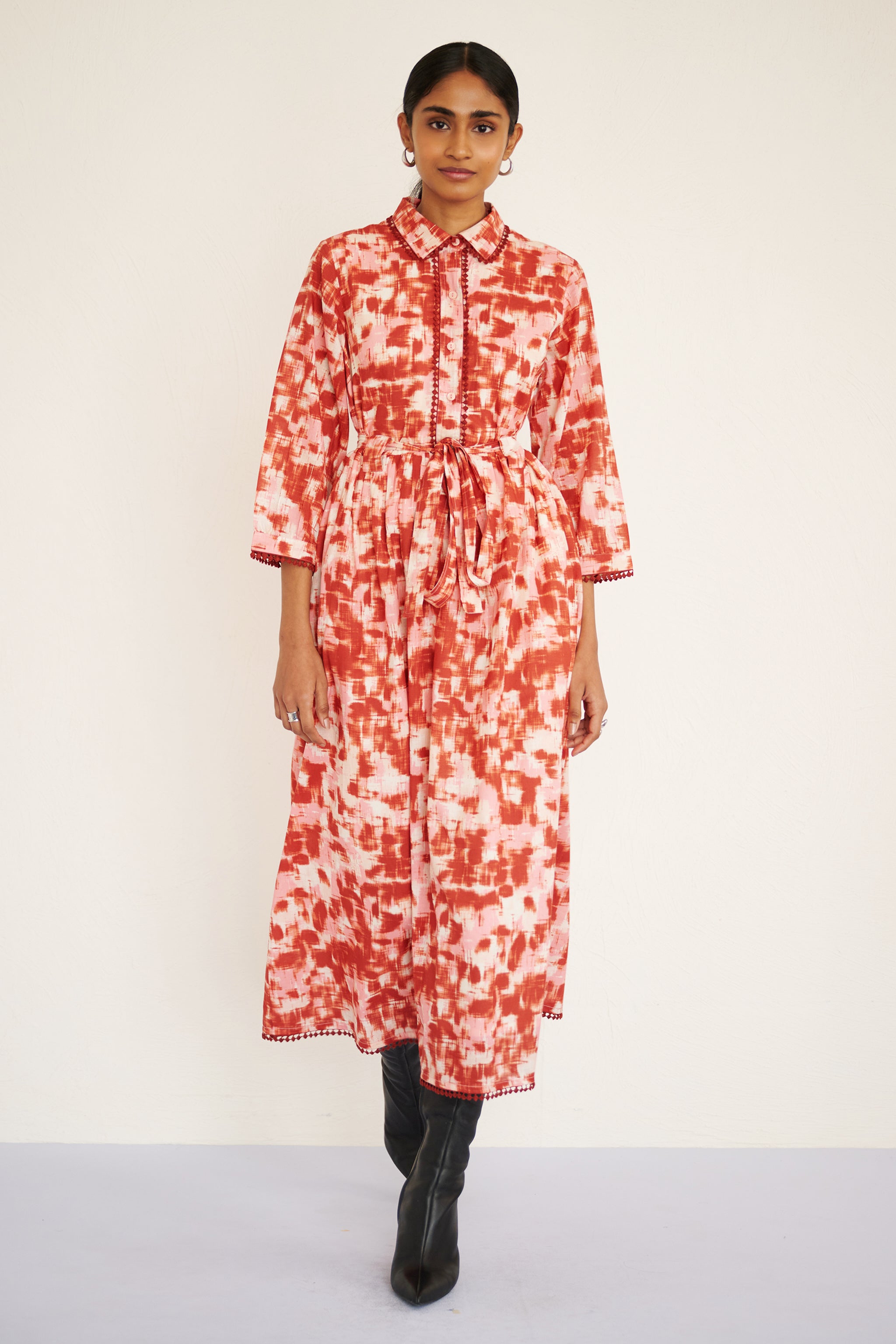 Front view of woman walking. She is wearing Marlene Dress in Amur print, Honey color. It is a tailored cotton midi shirtdress with lace trim at the collar, placket, and hem, featuring an ikat-inspired animal print.