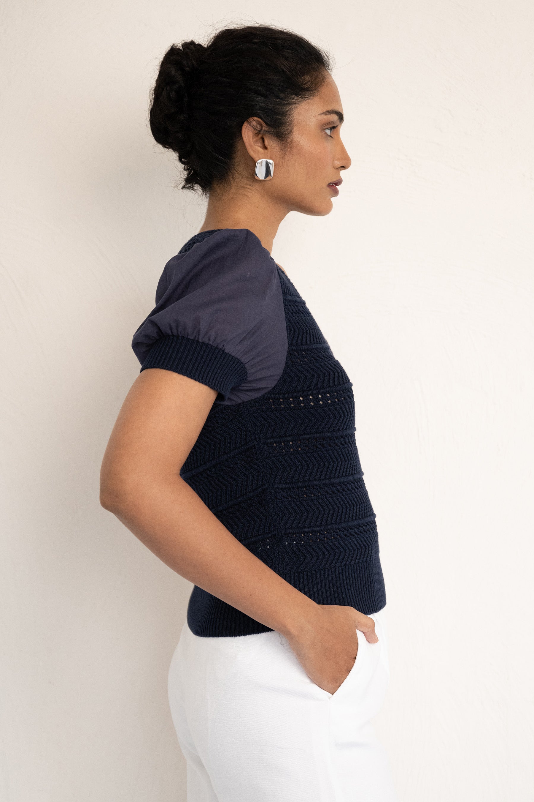 Side view close up of model wearing our Patti V neck oxford with right hand in pocket. Side view close up of model wearing our Patti V neck oxford with right hand in pocket.