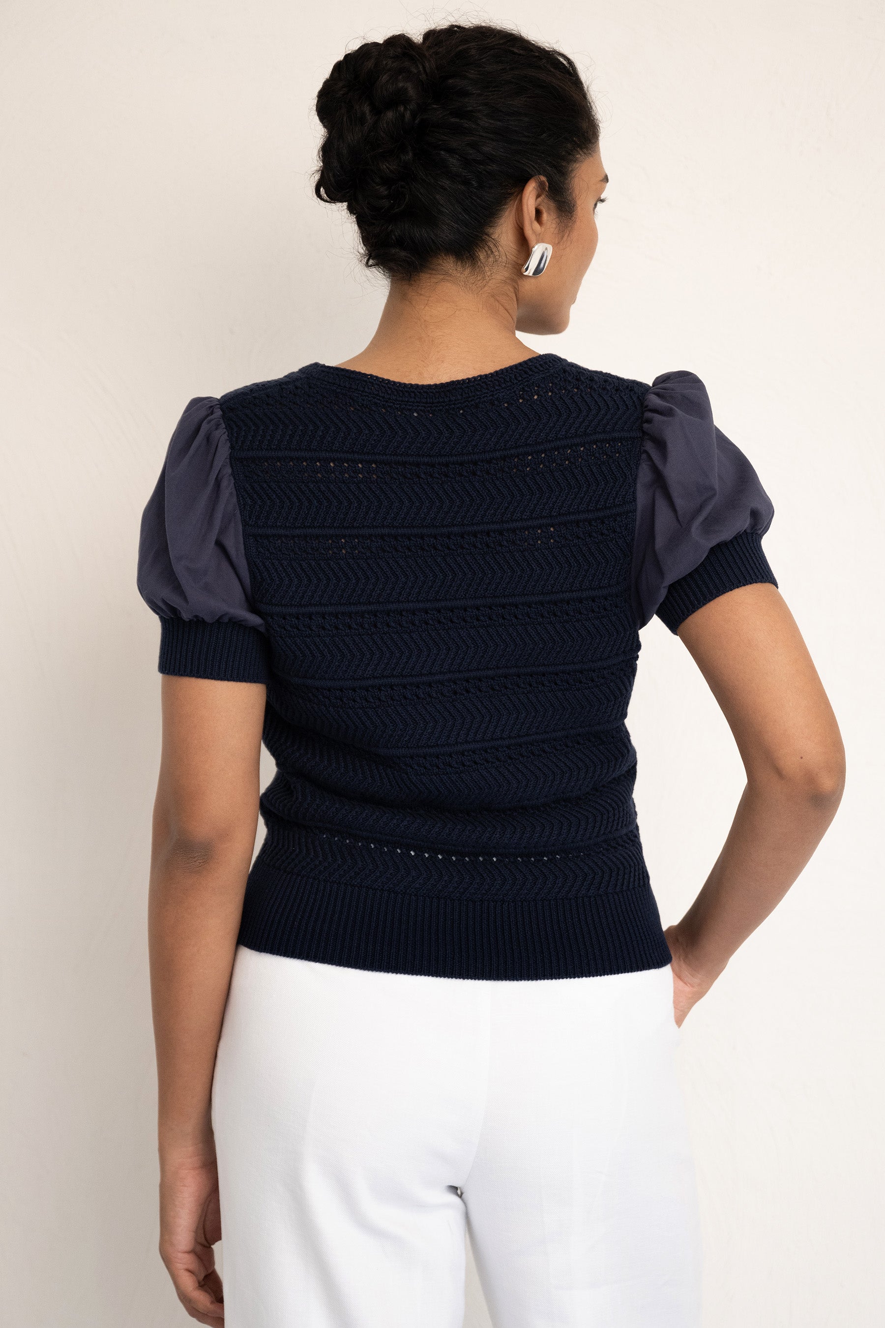 Back view close up of model wearing our Patti V neck oxford with right hand in pocket. Back view close up of model wearing our Patti V neck oxford with right hand in pocket.