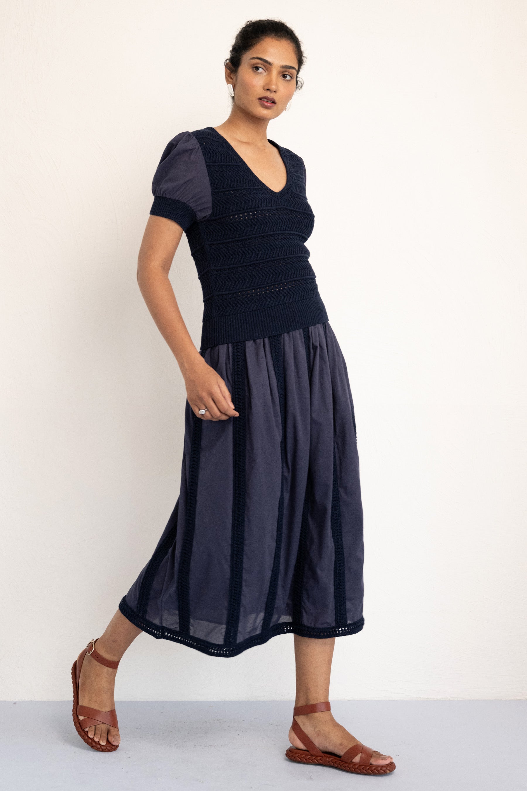 Model walking sideways waring Patti Vneck Oxford Knit top styled with a similar skirt . Model walking sideways waring Patti Vneck Oxford Knit top styled with a similar skirt .