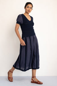 Model walking sideways waring Patti Vneck Oxford Knit top styled with a similar skirt . Model walking sideways waring Patti Vneck Oxford Knit top styled with a similar skirt .