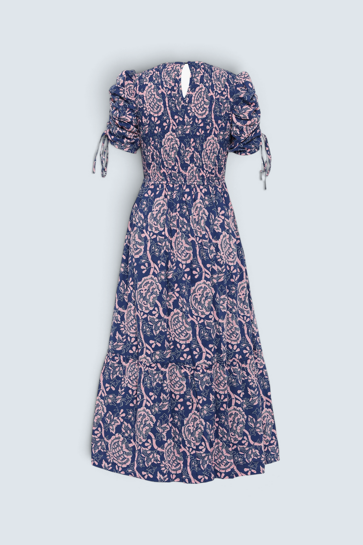 Back view of Banjanan Queenie midi dress in indigo with pink floral Coromandel print, smocked bodice, and drawstring sleeves.