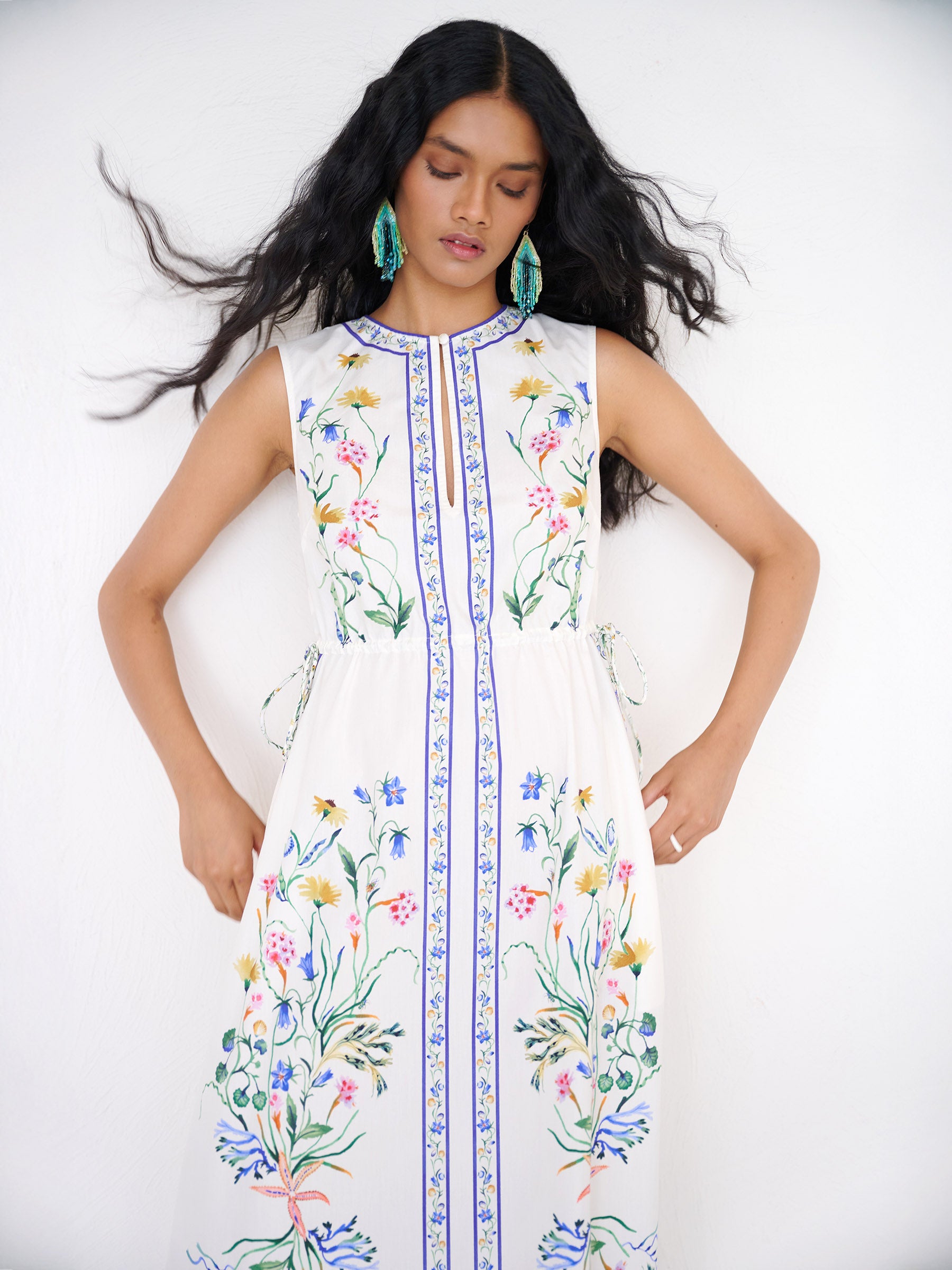 Front view close up of a woman standing. She is wearing the Rhonda column dress in Tidepool print. It features a crewneck with a fabric-covered button and keyhole detail, side drawstrings with gold caps, and side-seam pockets.