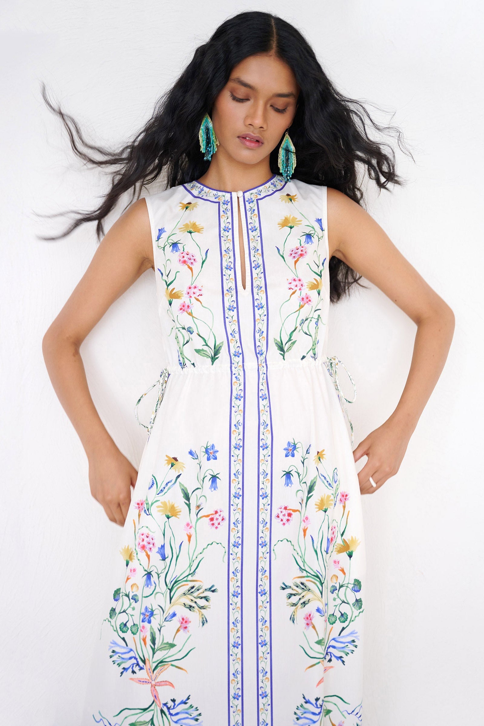 Front view close up of a woman standing wearing the Rhonda column dress in Tidepool print, featuring side drawstrings with gold caps, front keyhole button, and side-seam pockets.