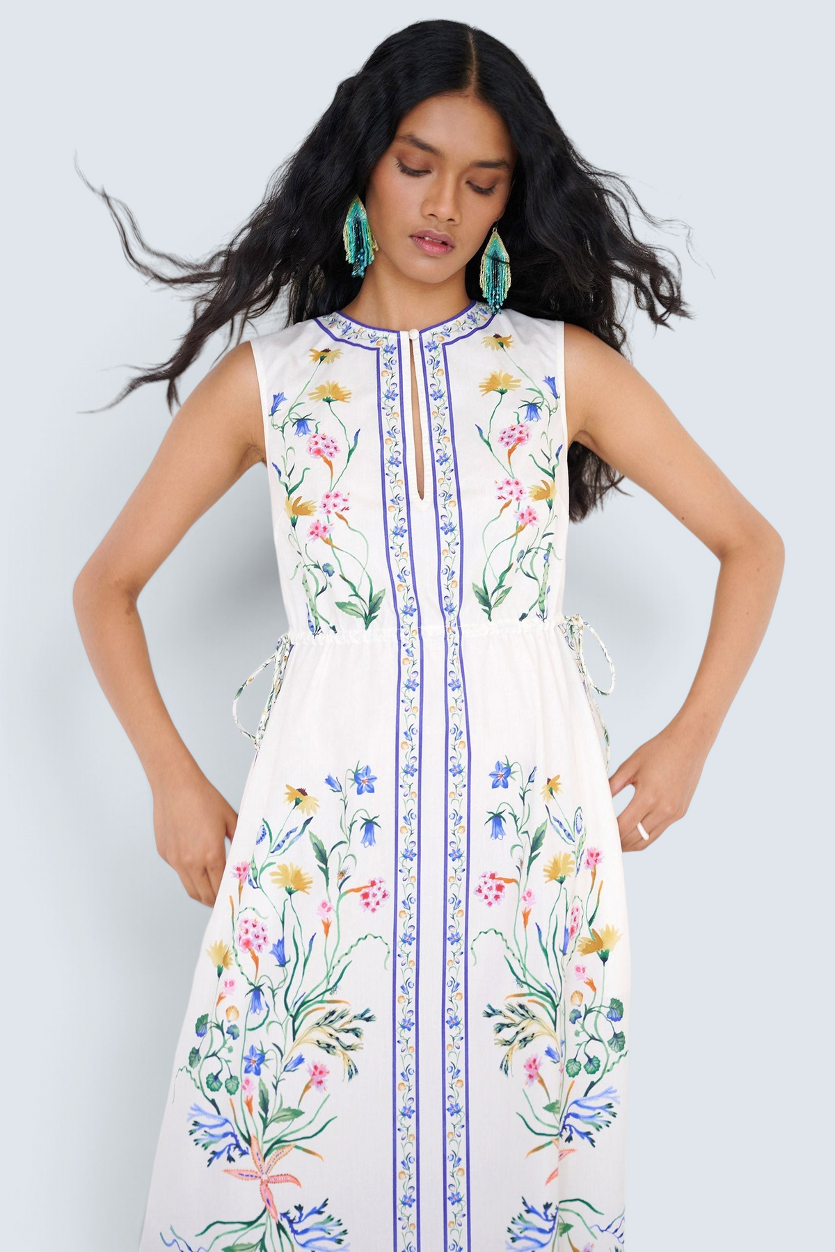 Front view close up of a woman standing wearing the Rhonda column dress in Tidepool print, featuring side drawstrings with gold caps, front keyhole button, and side-seam pockets.
