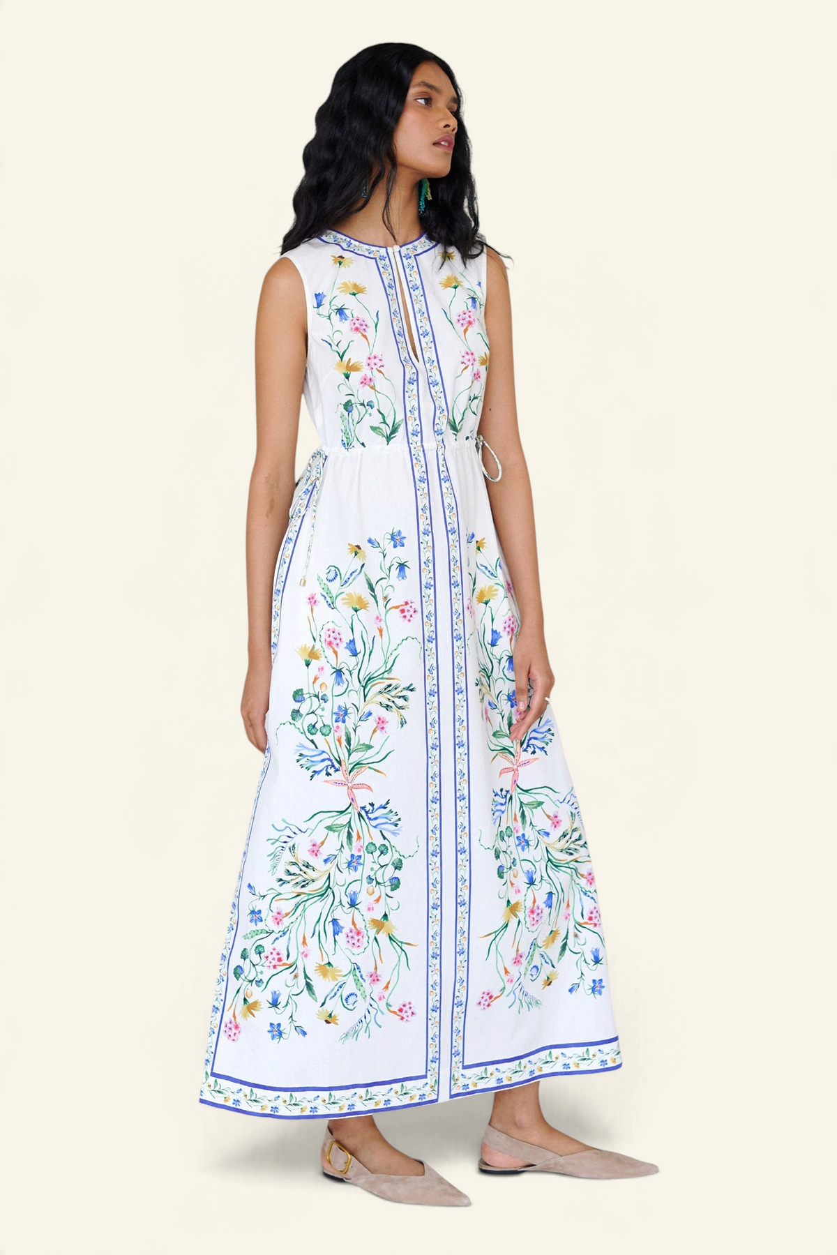 Front view of a woman standing looking sideways. She is wearing the Rhonda column dress in Tidepool print. It features a crewneck with a fabric-covered button and keyhole detail, side drawstrings with gold caps, and side-seam pockets.