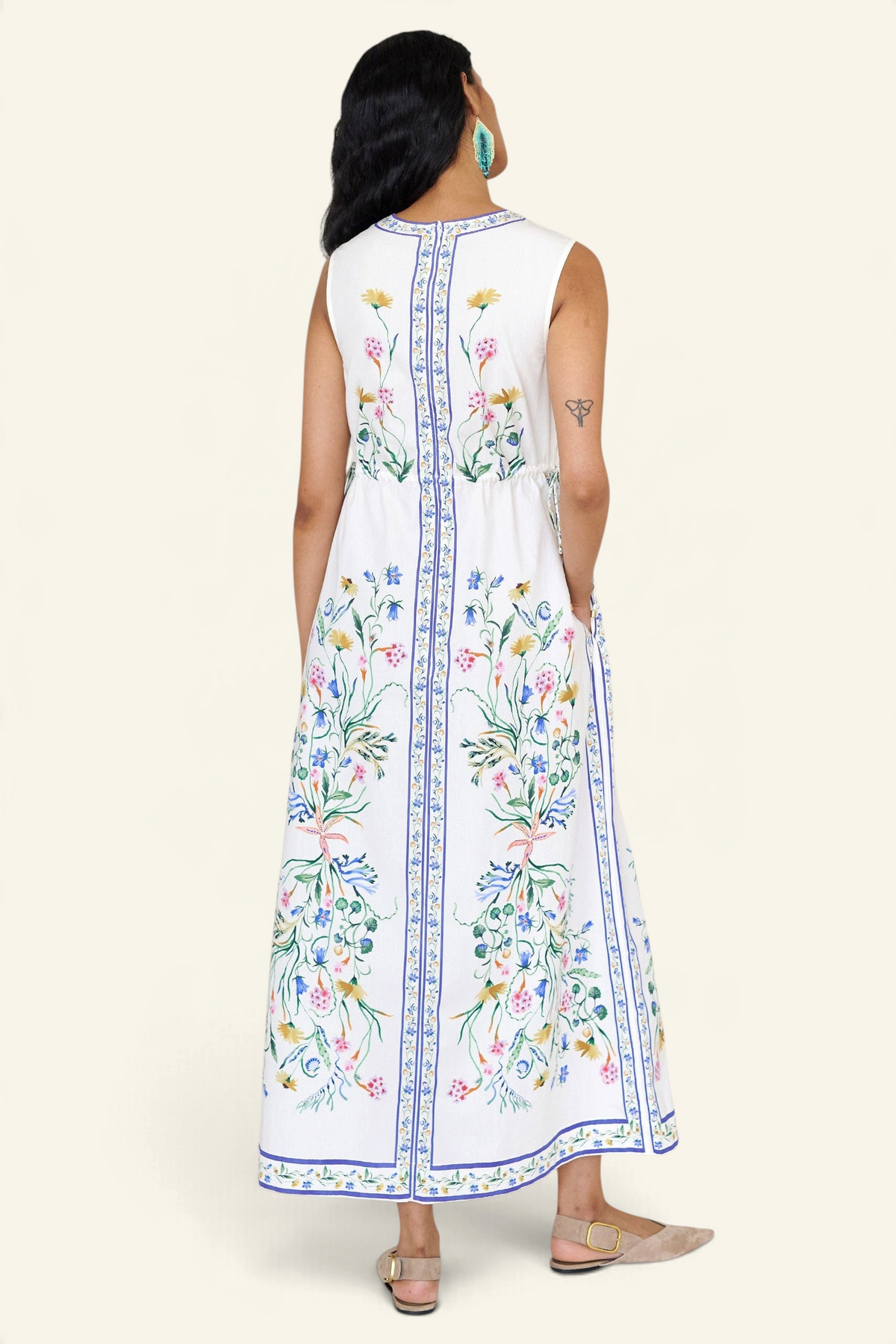 Back view of a woman standing wearing the Rhonda column dress in Tidepool print, featuring side drawstrings with gold caps, front keyhole button, and side-seam pockets.