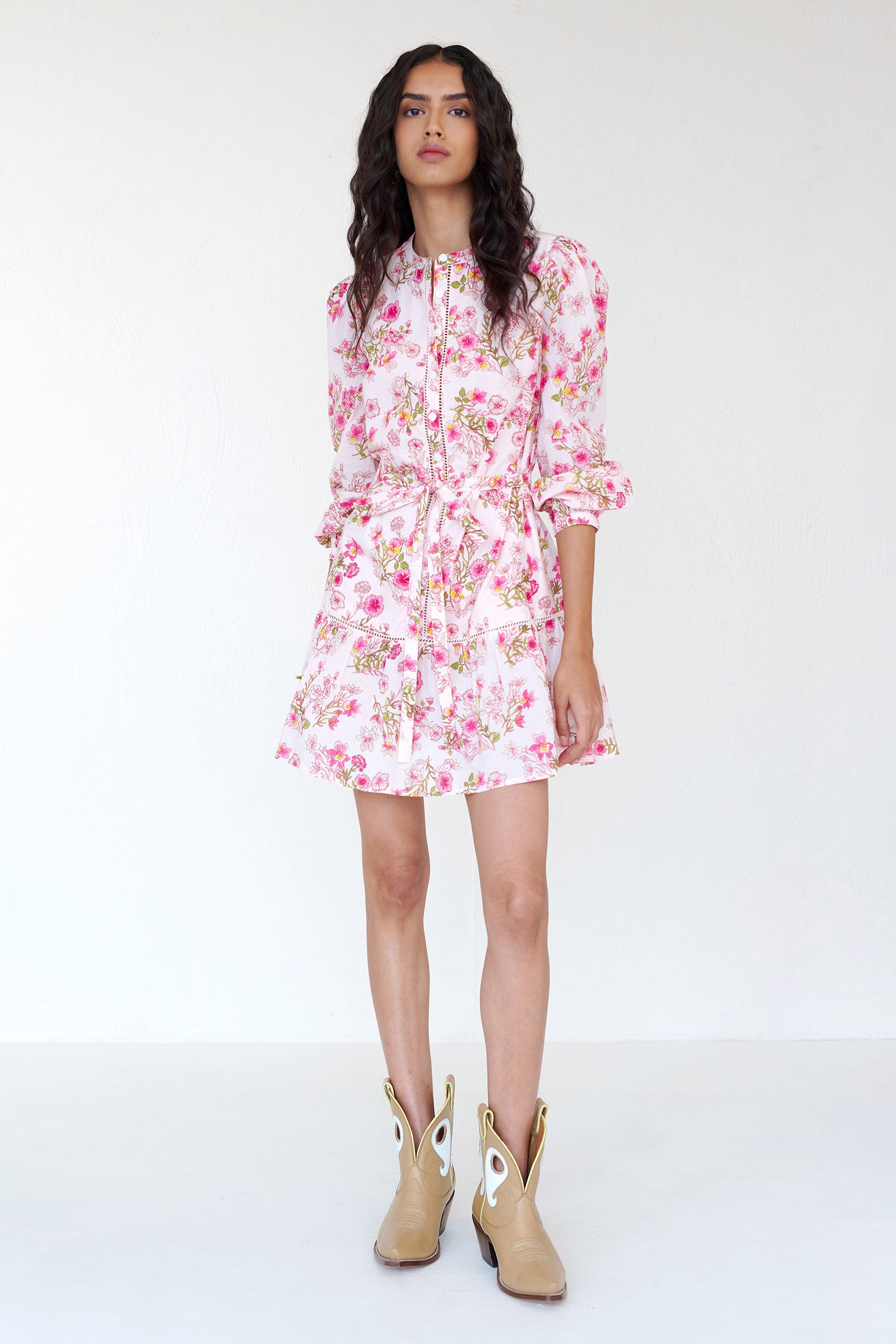 Front view of a woman standing wearing the Roma mini shirtdress in Burdock floral print. It features ladder lace detailing, detachable belt & side-seam pockets.