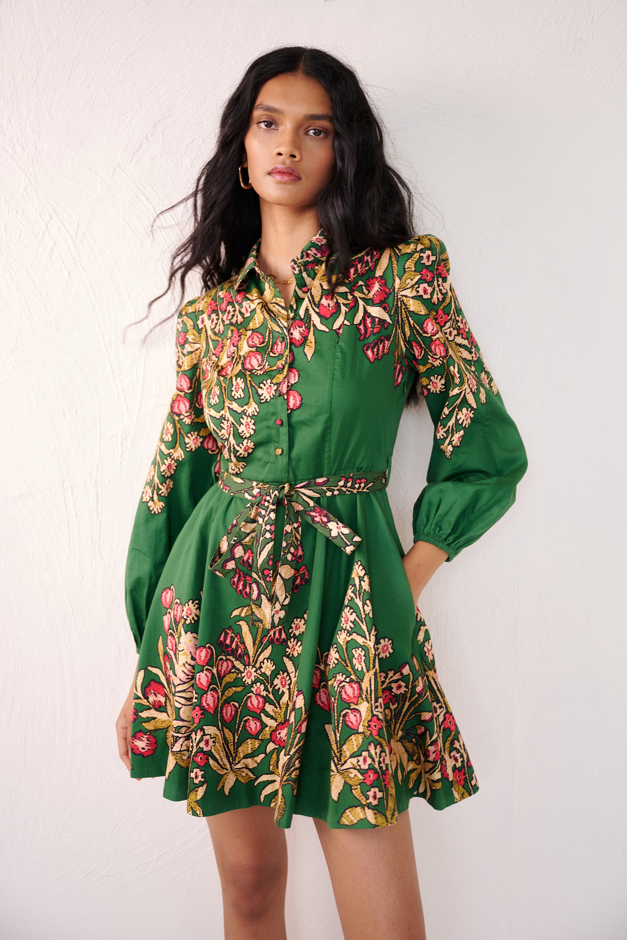 Front view close up of woman standing. She is wearing the Rowena mini shirt dress in Unicorn Tapestry print. It features a fitted bodice, delicate collar, lantern sleeves, short hem, side-seam pockets, and 15th-century-inspired enchanted garden motifs from the Scottish Highlands.