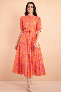 Front view of model stepping forward wearing a full length Saylor Dress in Gaia Nectarine print. Front view of model stepping forward wearing a full length Saylor Dress in Gaia Nectarine print.