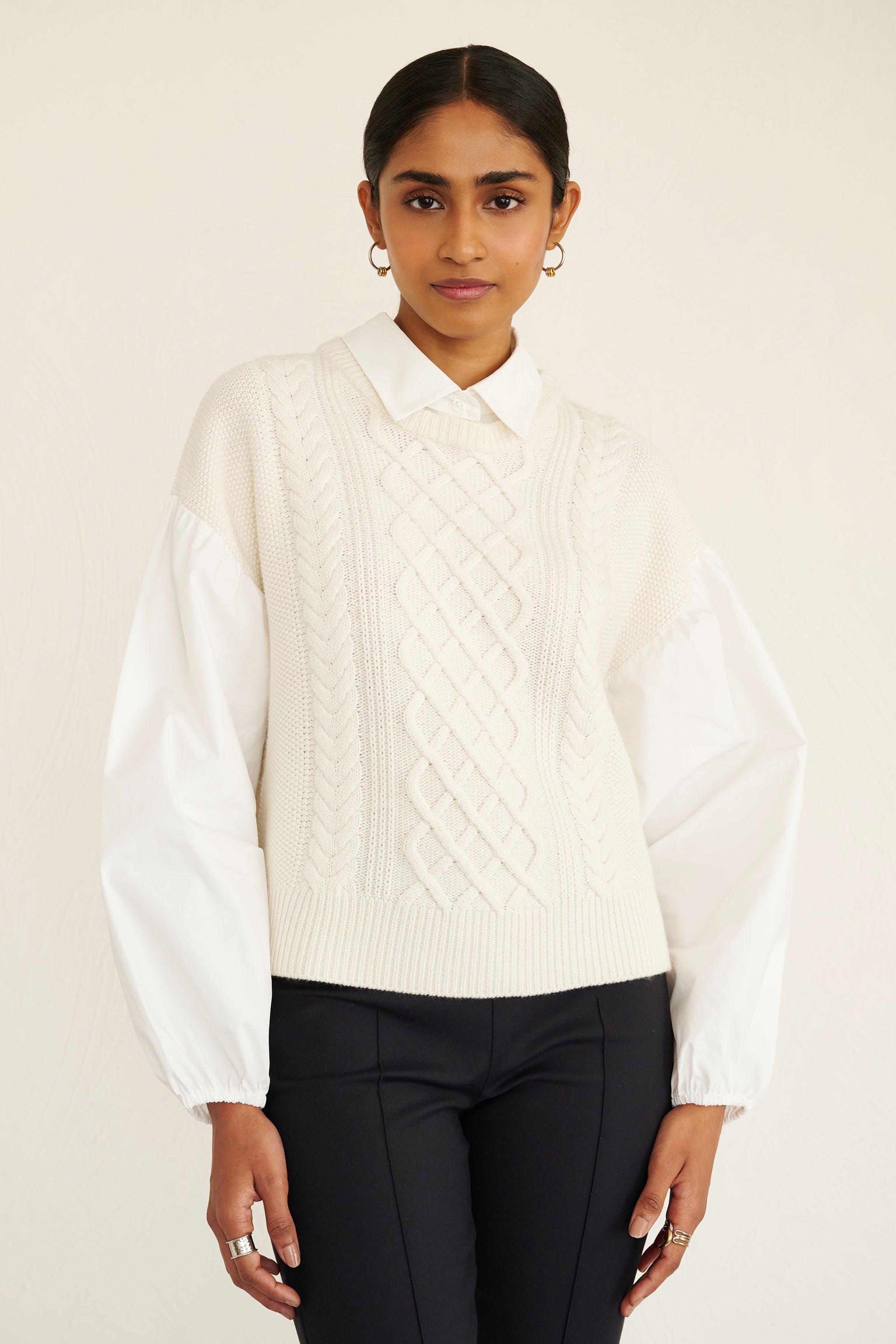 Front view of woman wearing a cable knit sweater with poplin shirt collar and sleeves, featuring elastic cuffs for shape and a layered look.