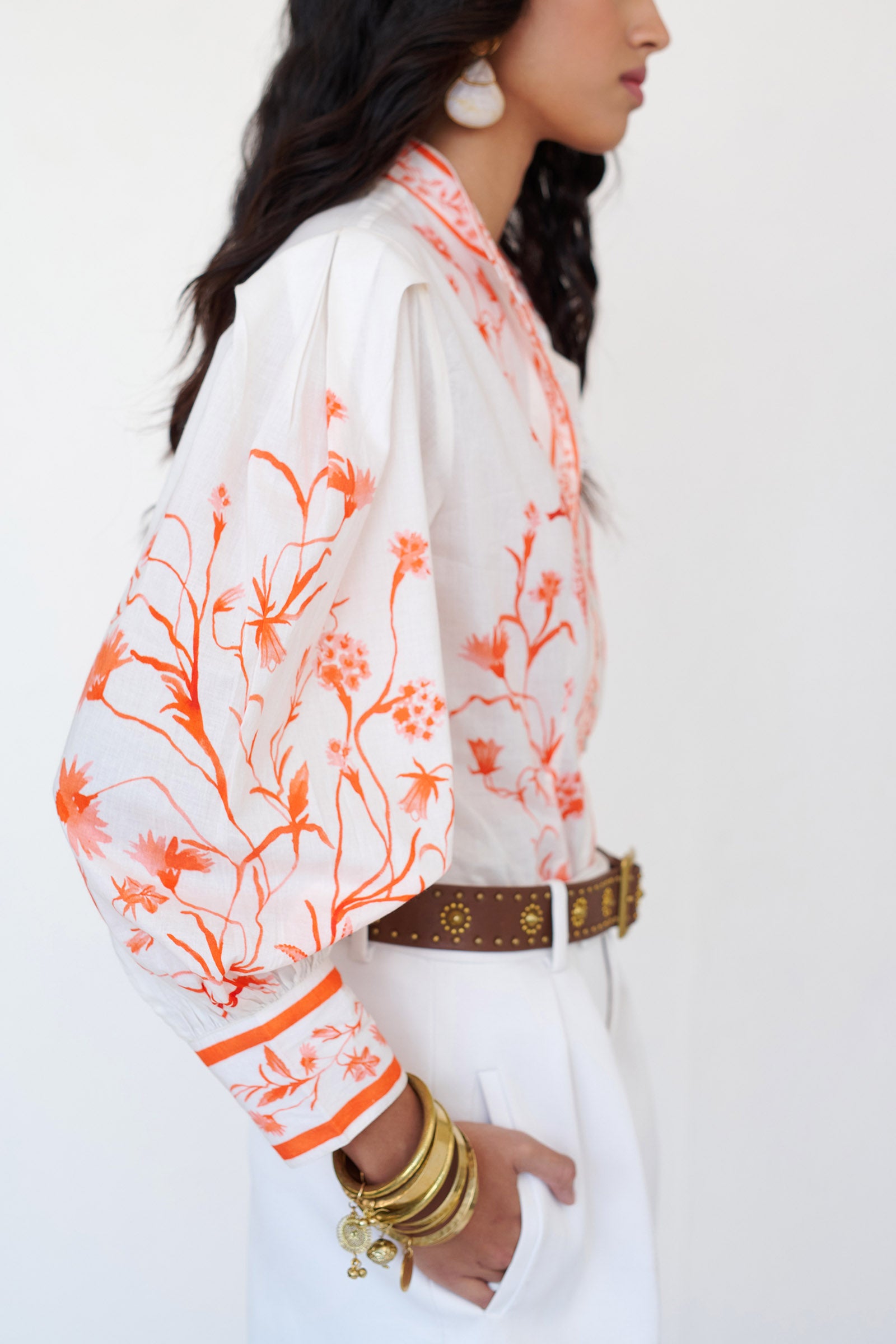 Side view of woman wearing the Tilly top with a stand collar, fabric-covered buttons, elegant sleeves, and the Tidepool print featuring seahorses, shells, and oyster catchers.