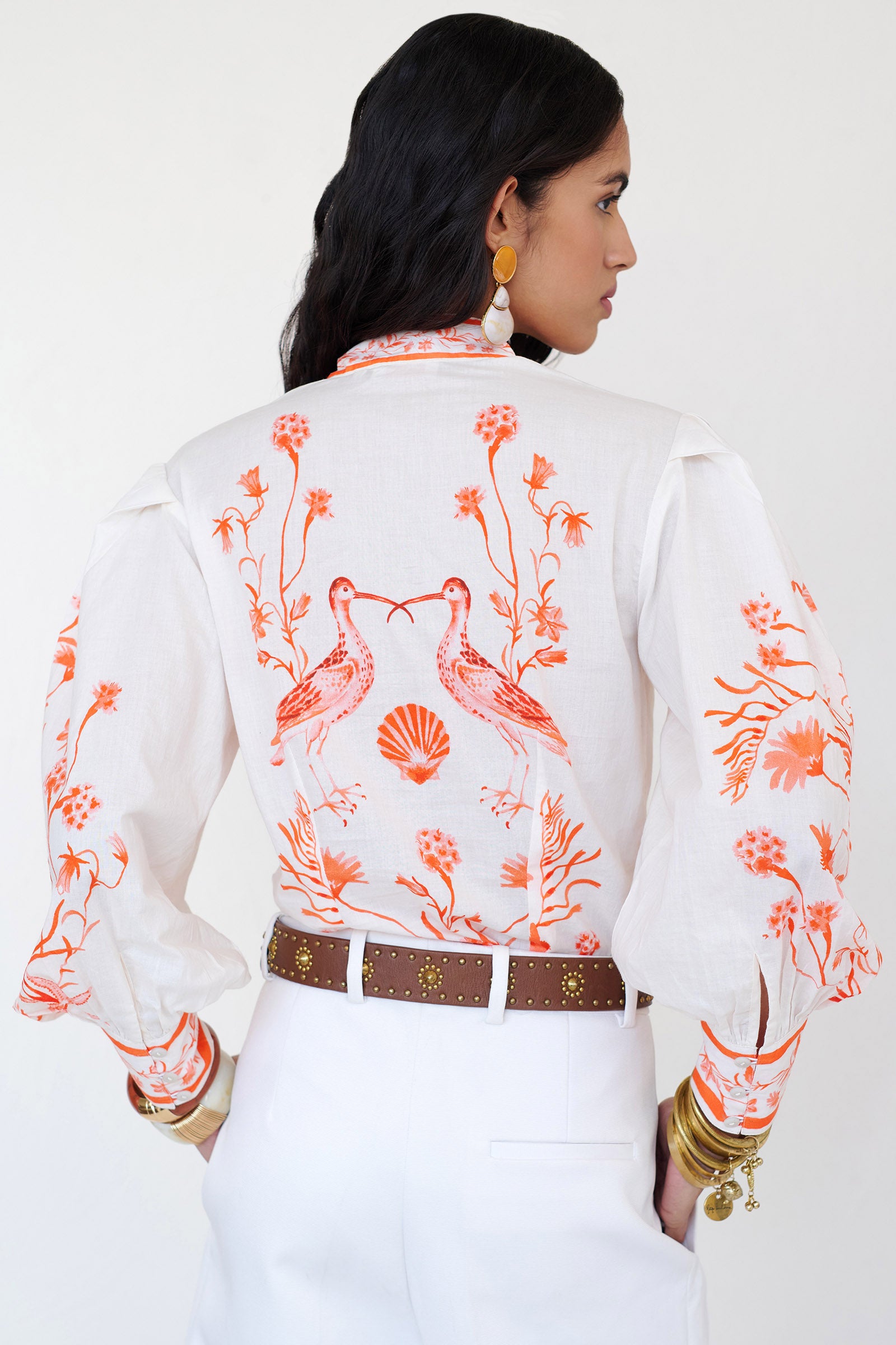Back view of woman wearing the Tilly top with a stand collar, fabric-covered buttons, elegant sleeves, and the Tidepool print featuring seahorses, shells, and oyster catchers.