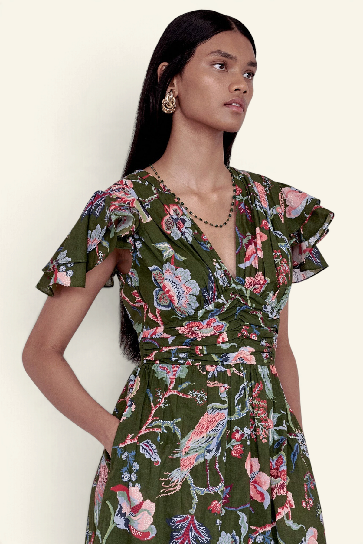 Banjanan Adele dress in moss green Chintz floral print with v-neck, pleated bust, and flutter sleeves on a model