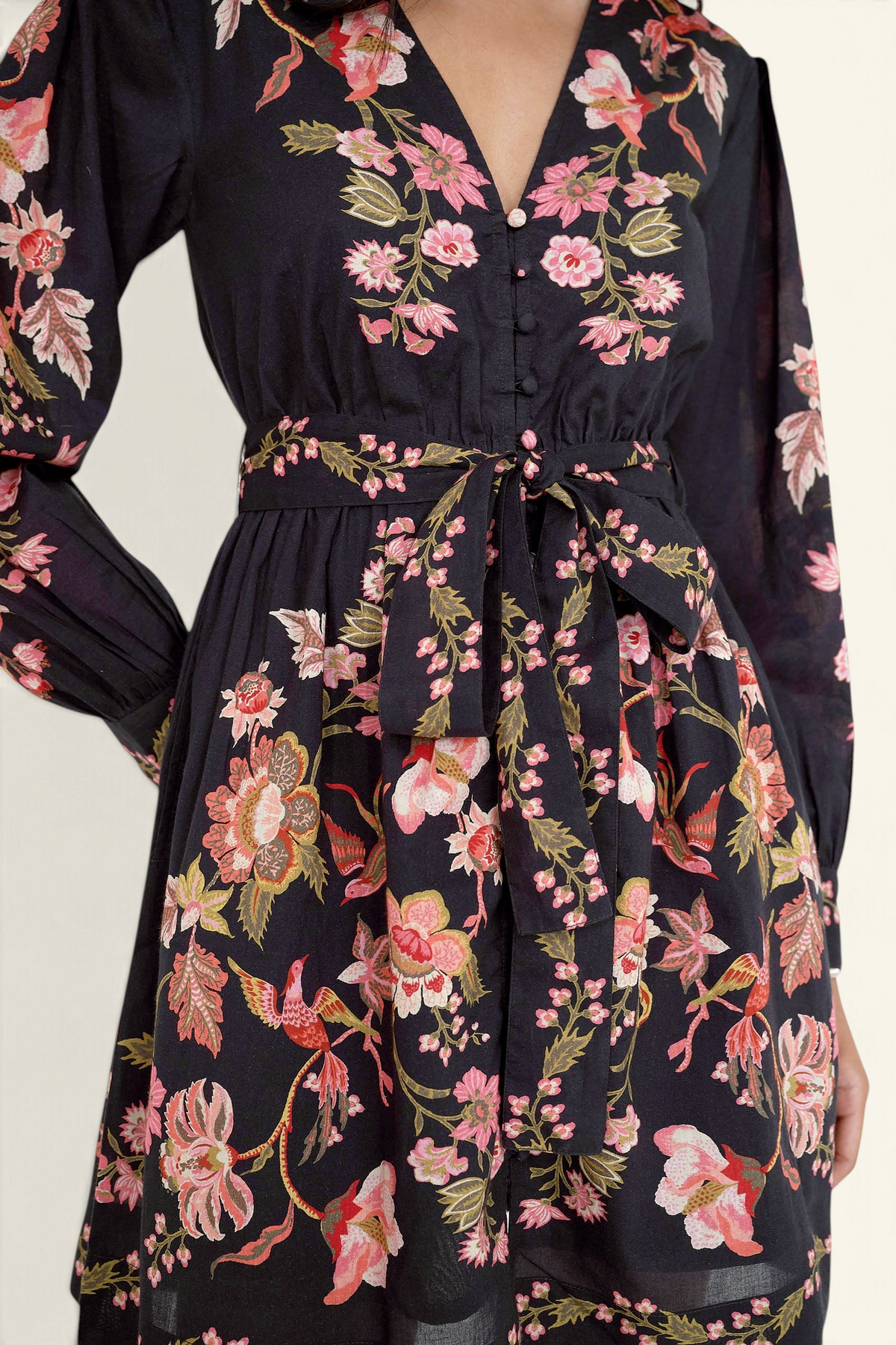 Close up of the Anne mini dress in Chintz print. It features long sleeves, an elasticated waist, fabric-covered buttons, a fabric belt, and side-seam pockets.