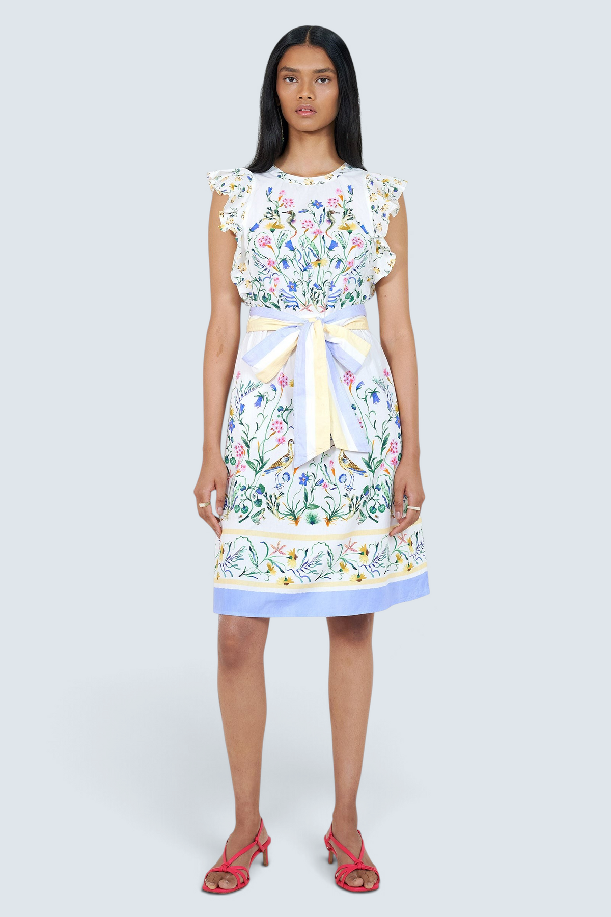 Banjanan Bulbul dress in Tidepool Grotto print with ruffled shoulders, floral pattern, and blue and yellow stripe belt.