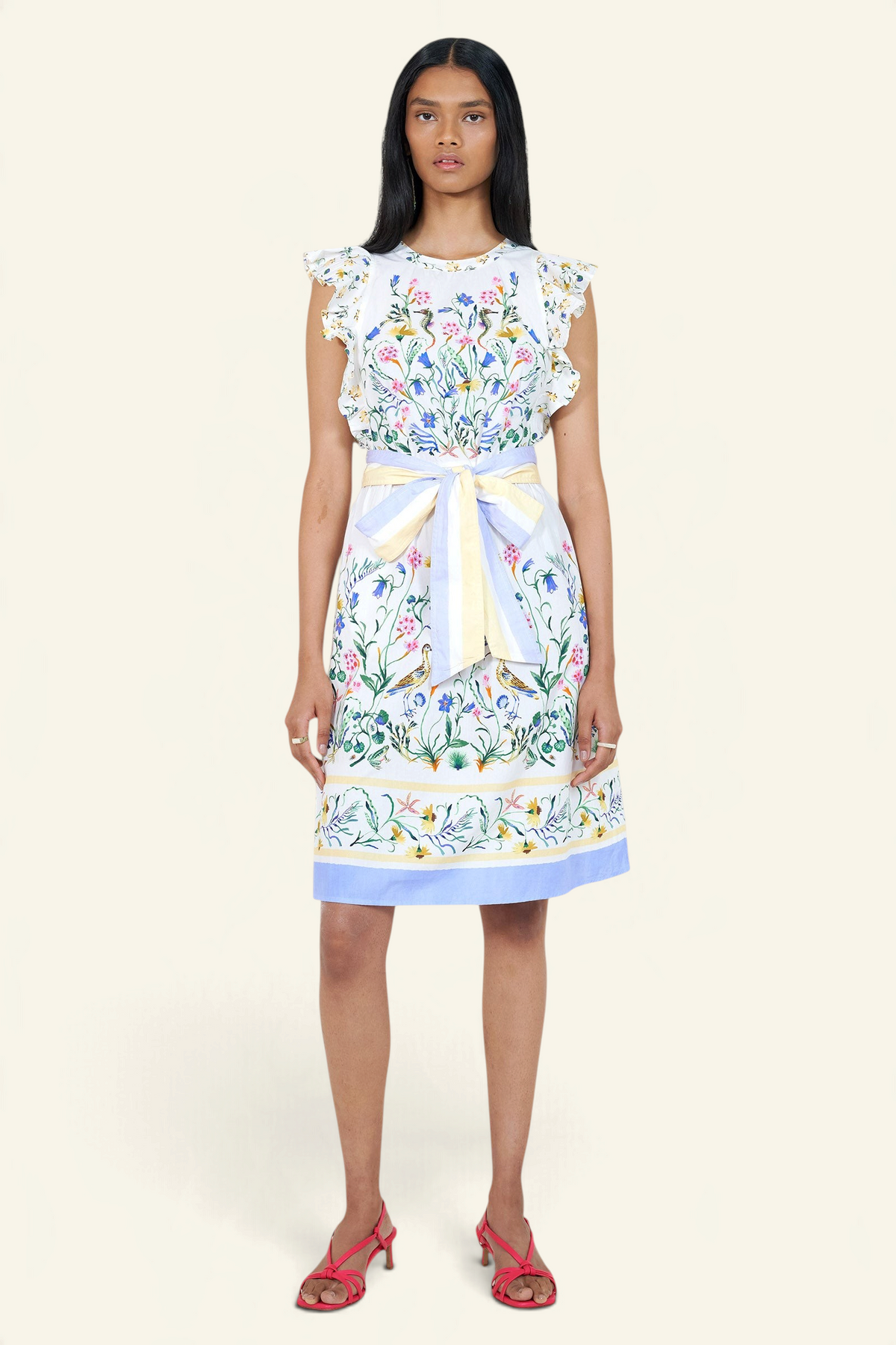Banjanan Bulbul dress in Tidepool Grotto print with ruffled shoulders, floral pattern, and blue and yellow stripe belt.