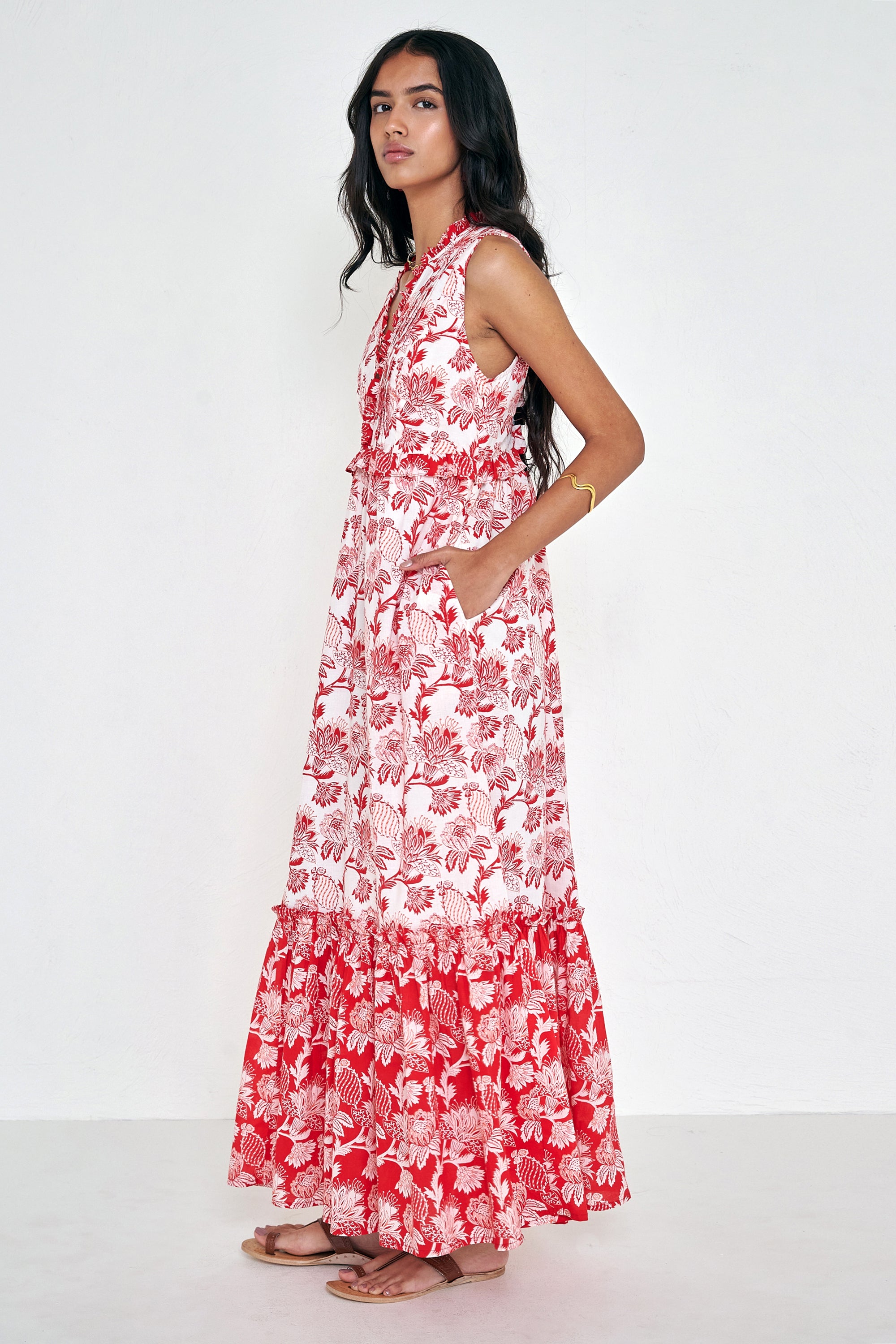 Side view of woman standing. She is wearing the Constance dress in the Lizzie print, featuring an A-line silhouette, pleated neckline, soft frill details, and floral vine motifs inspired by Provence.