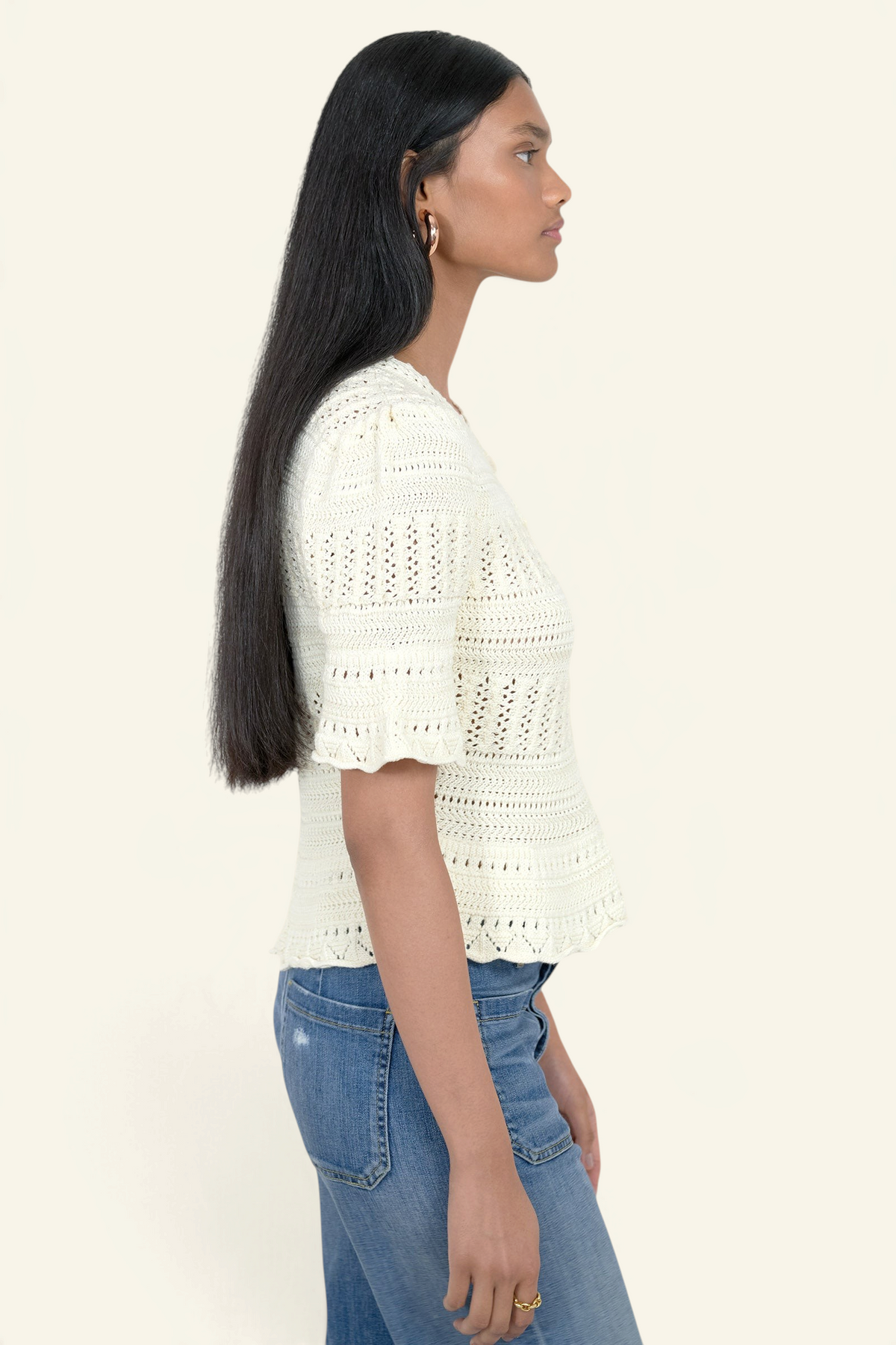 Model wearing a Banjanan ivory short sleeve cotton crochet cardigan with intricate trim detail, side profile view.