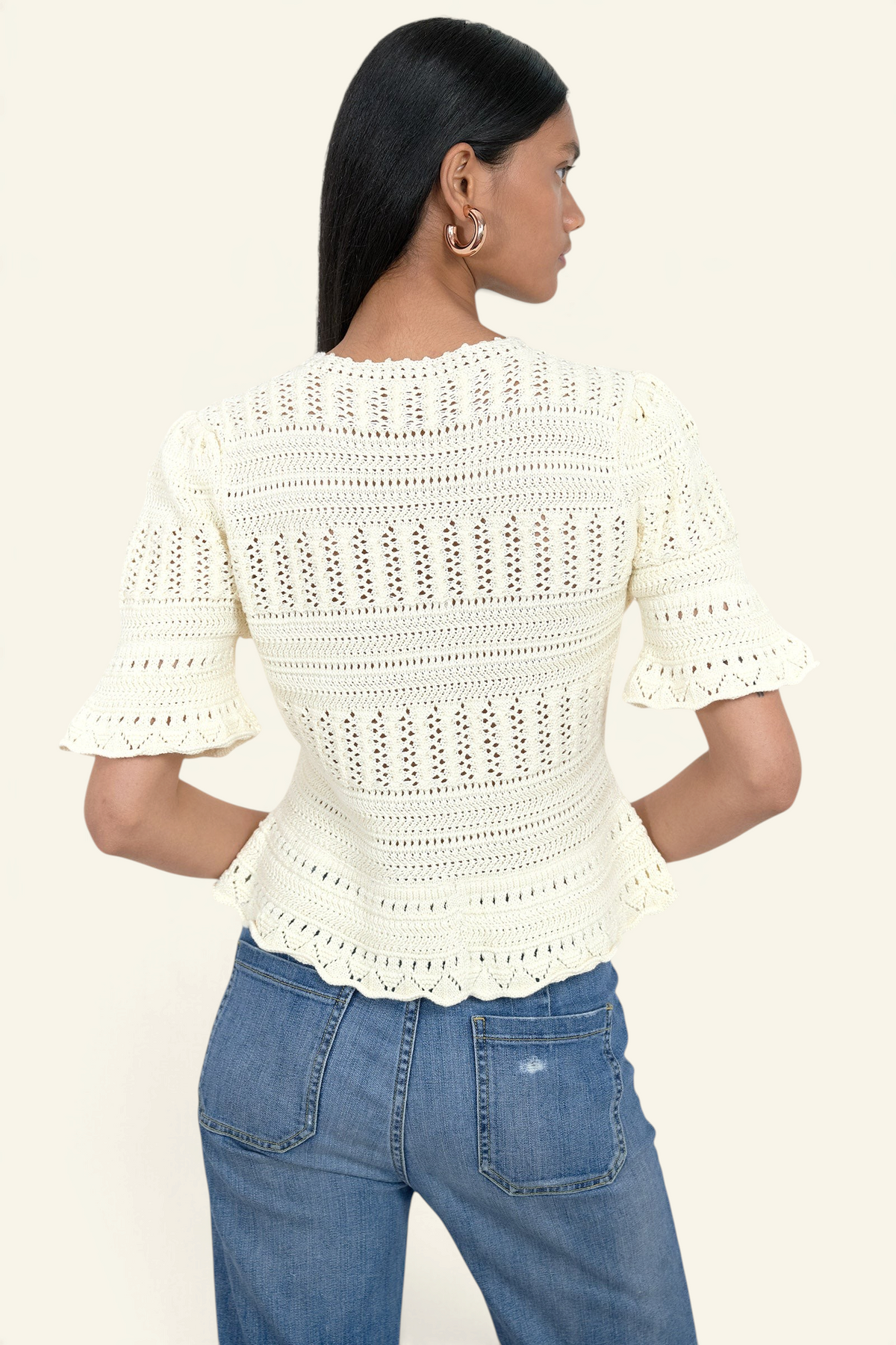 Banjanan ivory cotton short sleeve cardigan with intricate hand-crocheted trim and ruffled sleeves, back view.