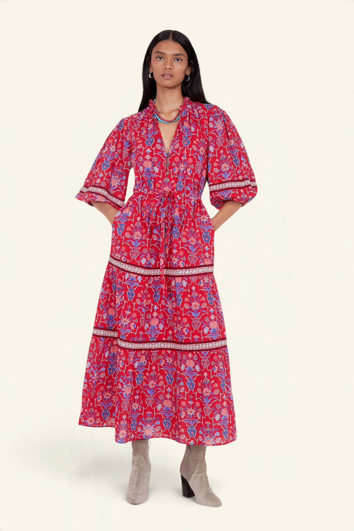 Front view of model standing. She is wearing the Liza dress in Floral Vase print. It features a tie neckline, soft ruffles, lace sleeve and skirt details, and a fabric belt.