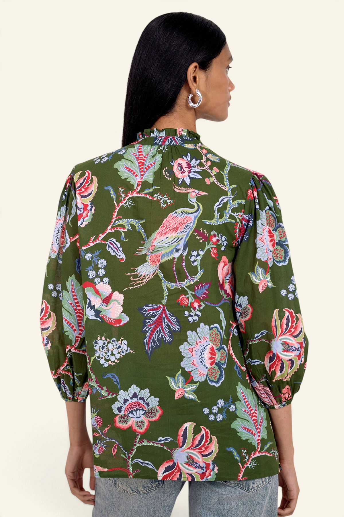 Back view of model standing. She is wearing the Lorna top in Chintz print, featuring a V-neck with a soft ruffle and tie, a loose flowing body, and slightly voluminous sleeves, paired with jeans.