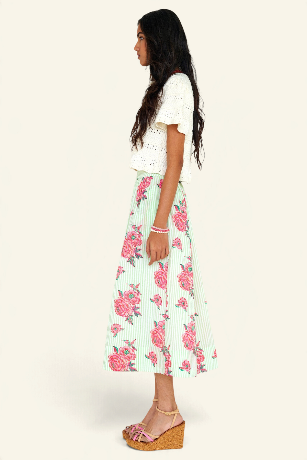 Side view of woman standing wearing the Magdalena skirt in the Eliza Rose print, featuring all-around pleats & hand block-printed floral motifs.