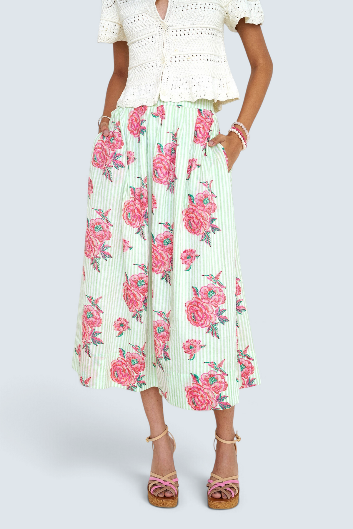 Front view close up of woman standing wearing the Magdalena skirt in the Eliza Rose print, featuring all-around pleats & hand block-printed floral motifs.