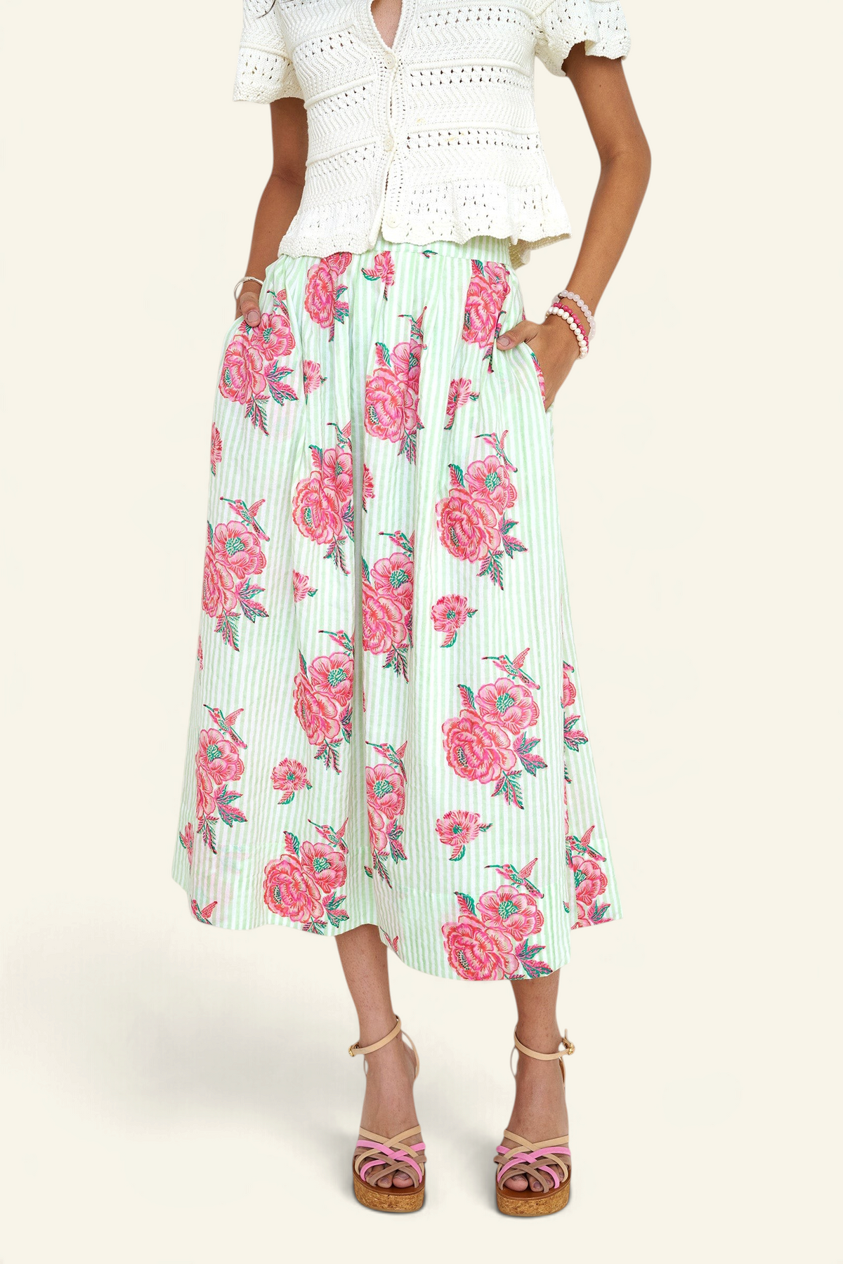 Front view close up of woman standing wearing the Magdalena skirt in the Eliza Rose print, featuring all-around pleats & hand block-printed floral motifs.