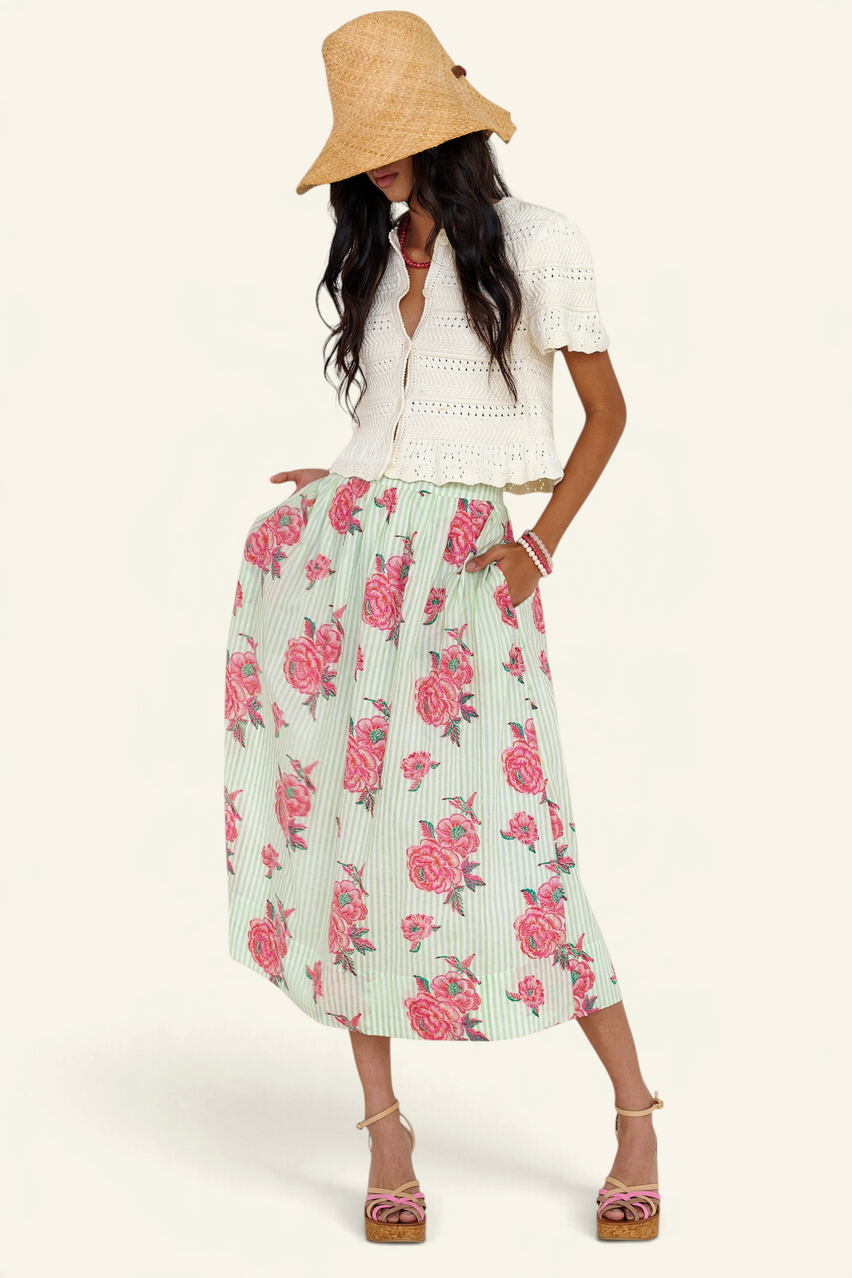 Front view of woman standing wearing the Magdalena skirt in the Eliza Rose print, featuring all-around pleats & hand block-printed floral motifs. Paired with laura crochet cardigan in ivory.