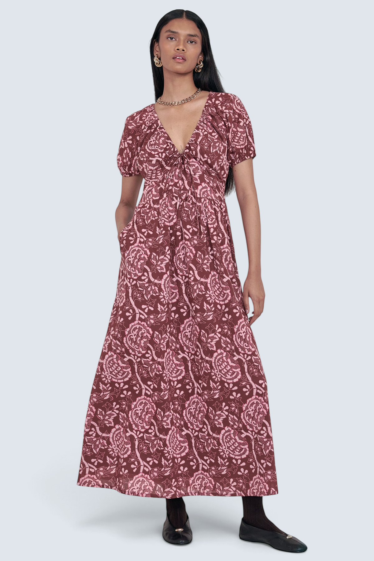 Front view of model standing. She is wearing the Norma dress in Coromandel print, featuring a drawstring neckline, elasticated sleeves, a flattering princess seam waist, and side-seam pockets.